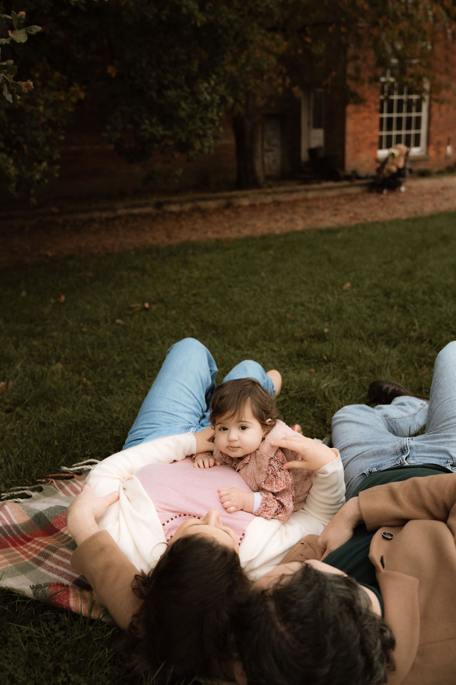 A baby in a parent's arms lying on a checkered blanket, enjoying  a cosy moment together