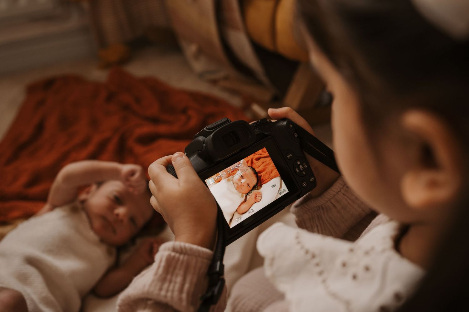 Child photographing their baby sibling during a relaxed lifestyle family photoshoot at home in Melbourne