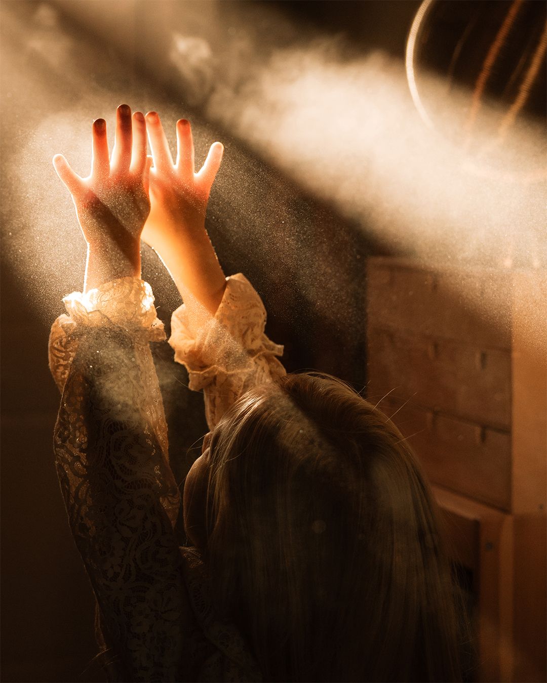 Child reaching toward sunlight indoors during a quiet documentary childhood photoshoot in Swadlincote