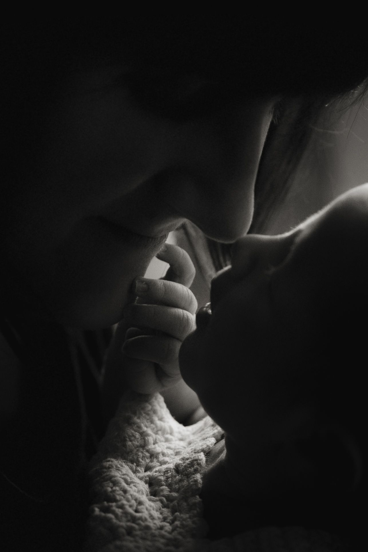 Parent touching noses with their newborn during a tender storytelling newborn photoshoot in black and white.