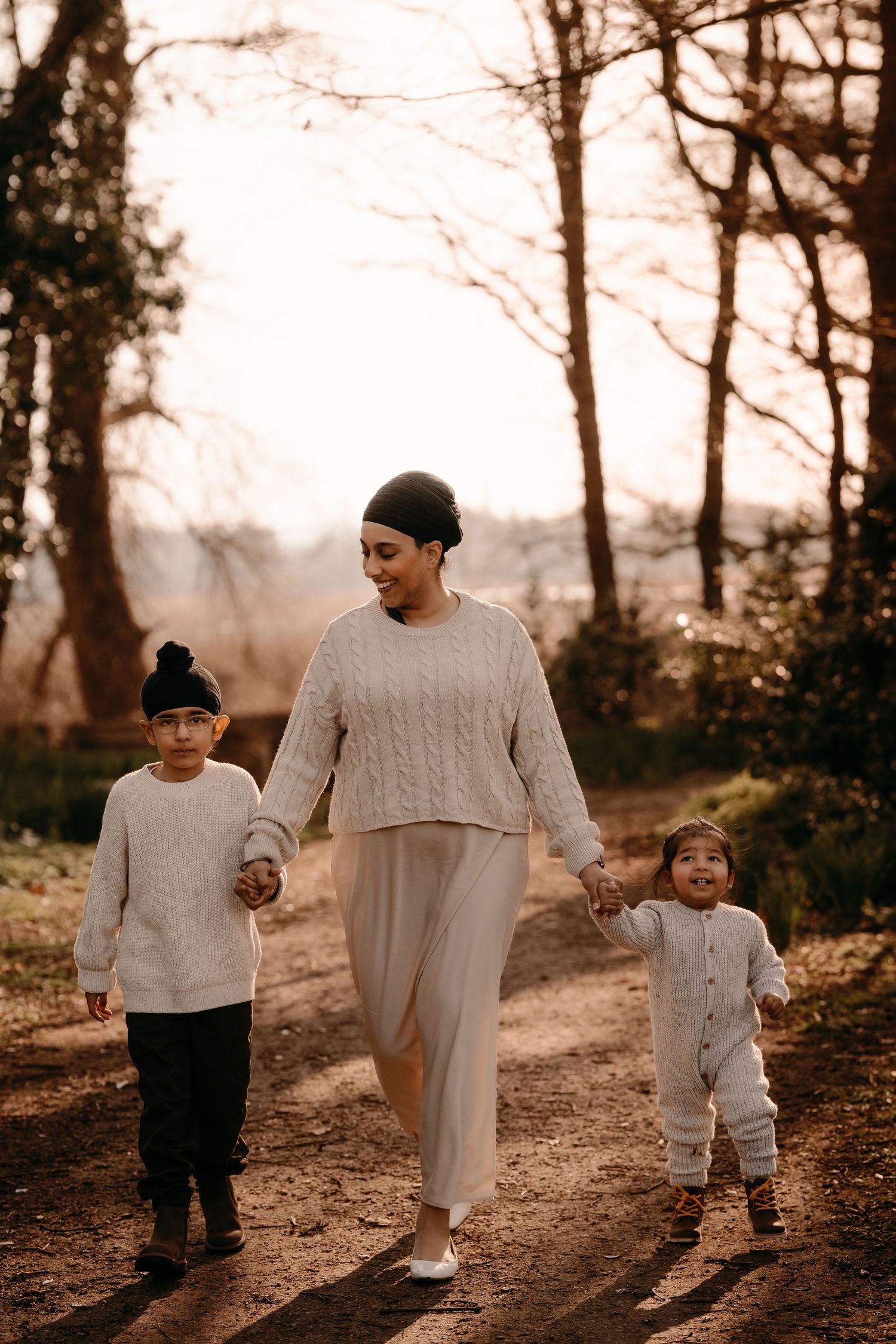 Mother walks hand in hand with her two children during a golden-hour family photoshoot in Swadlincote.