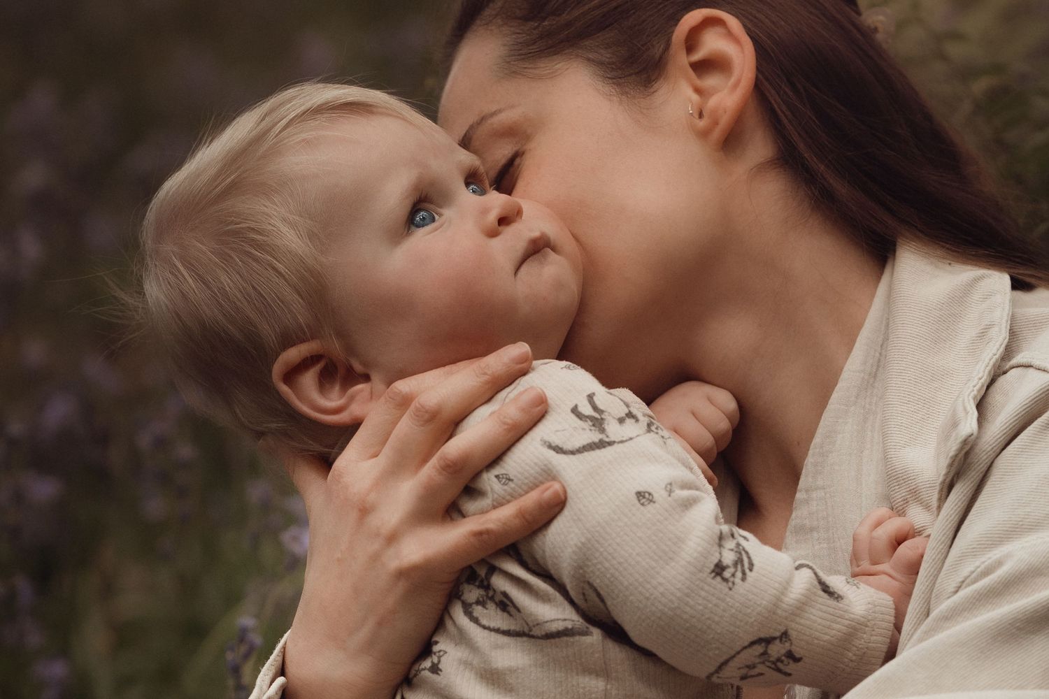 Mother holding her baby close during an intimate outdoor documentary motherhood photography session in Bluebells