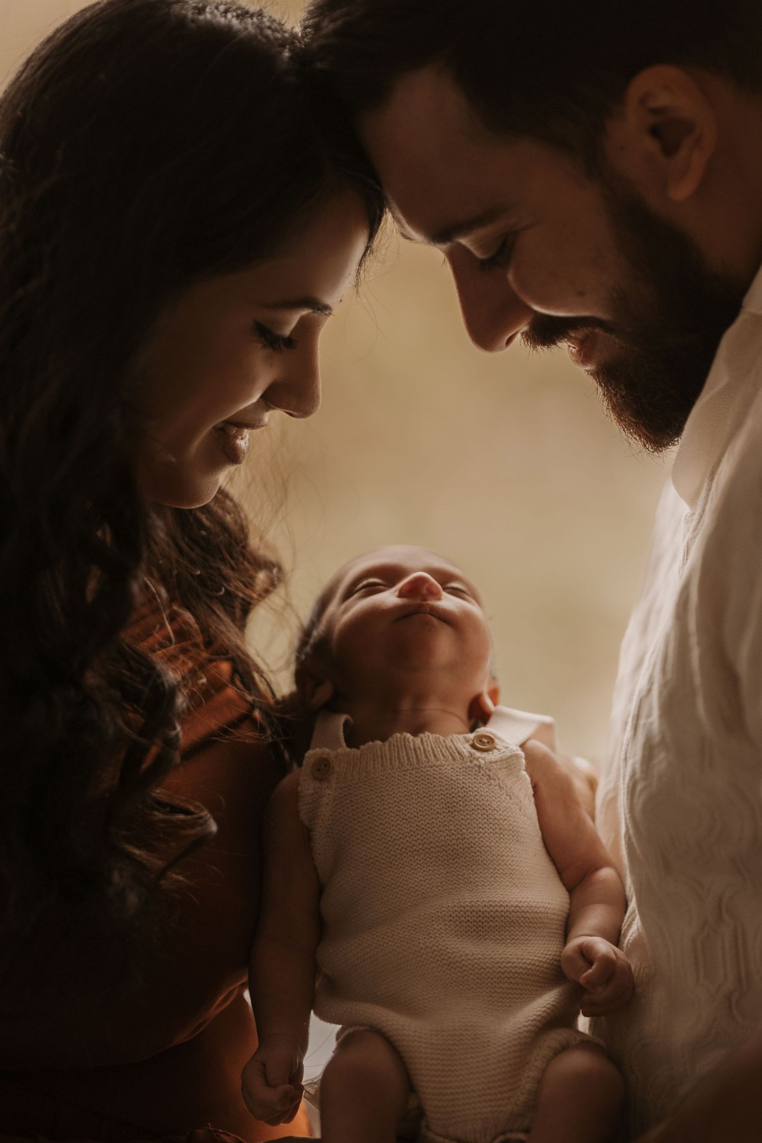 Parents gazing at their baby during an intimate storytelling newborn photoshoot filled with calm connection.