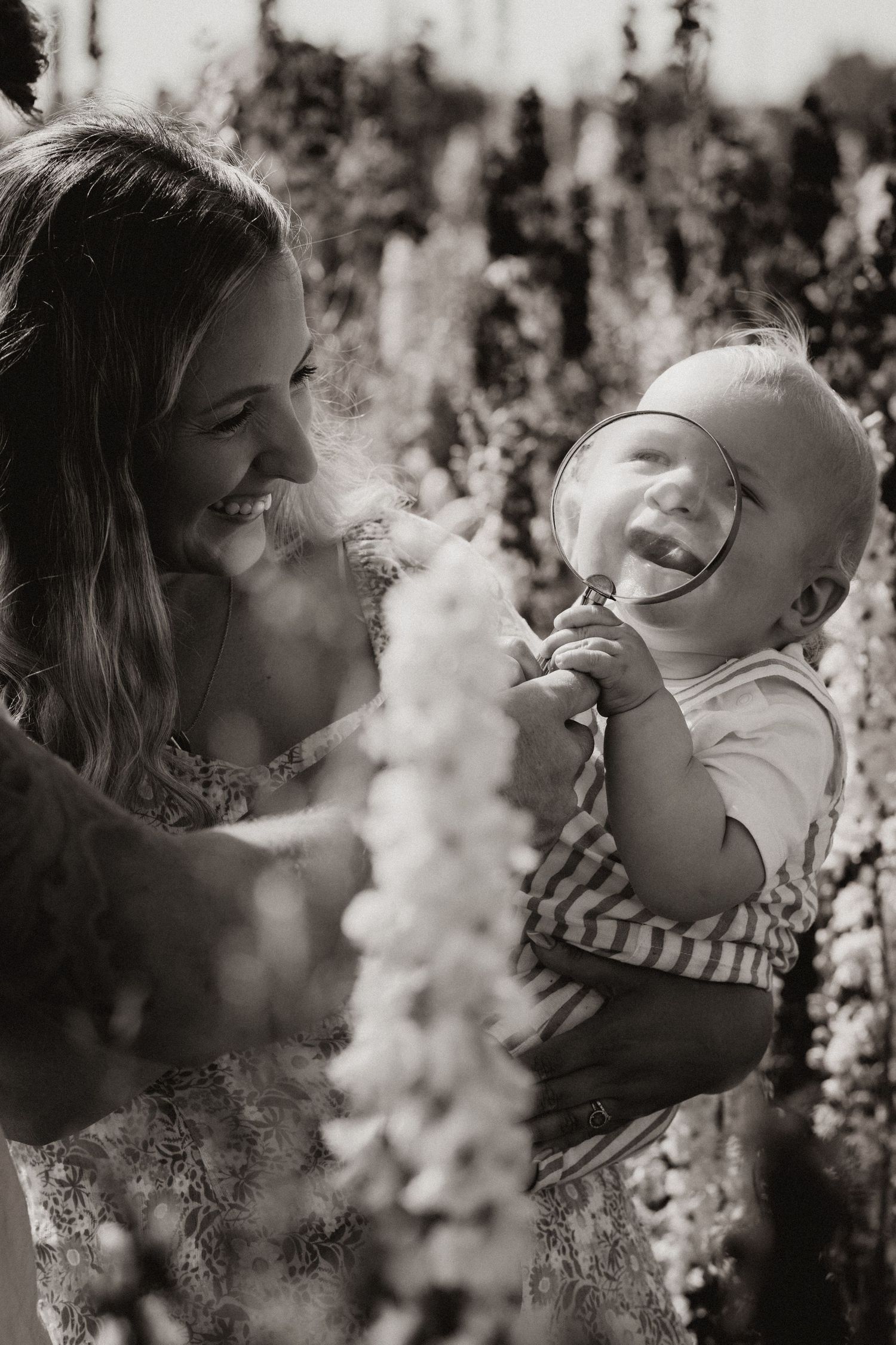 Mother holding her baby in a flower field during an outdoor documentary motherhood photography session in Confetti Field