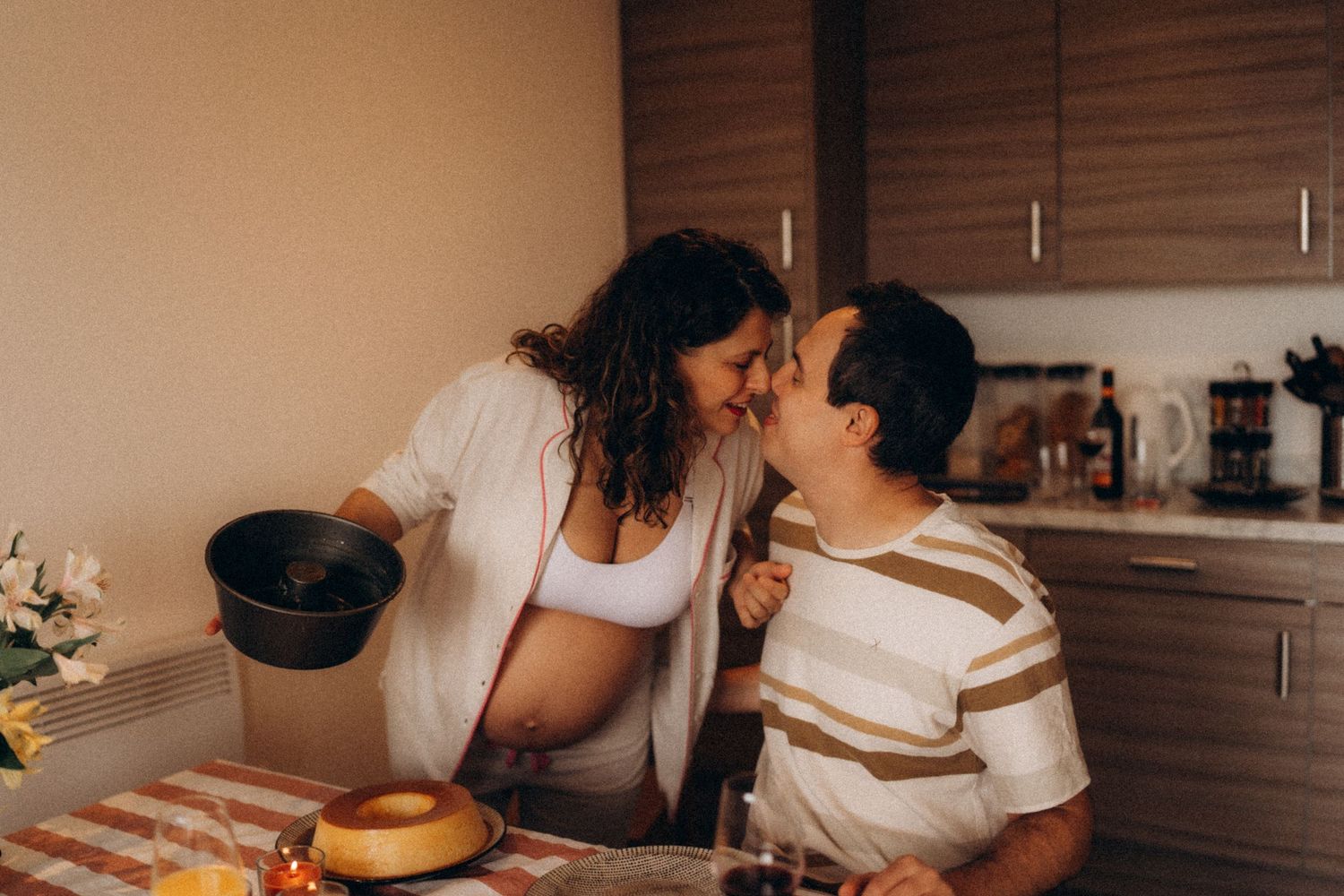Couple laughing together in their kitchen during a relaxed in-home lifestyle maternity photography session.