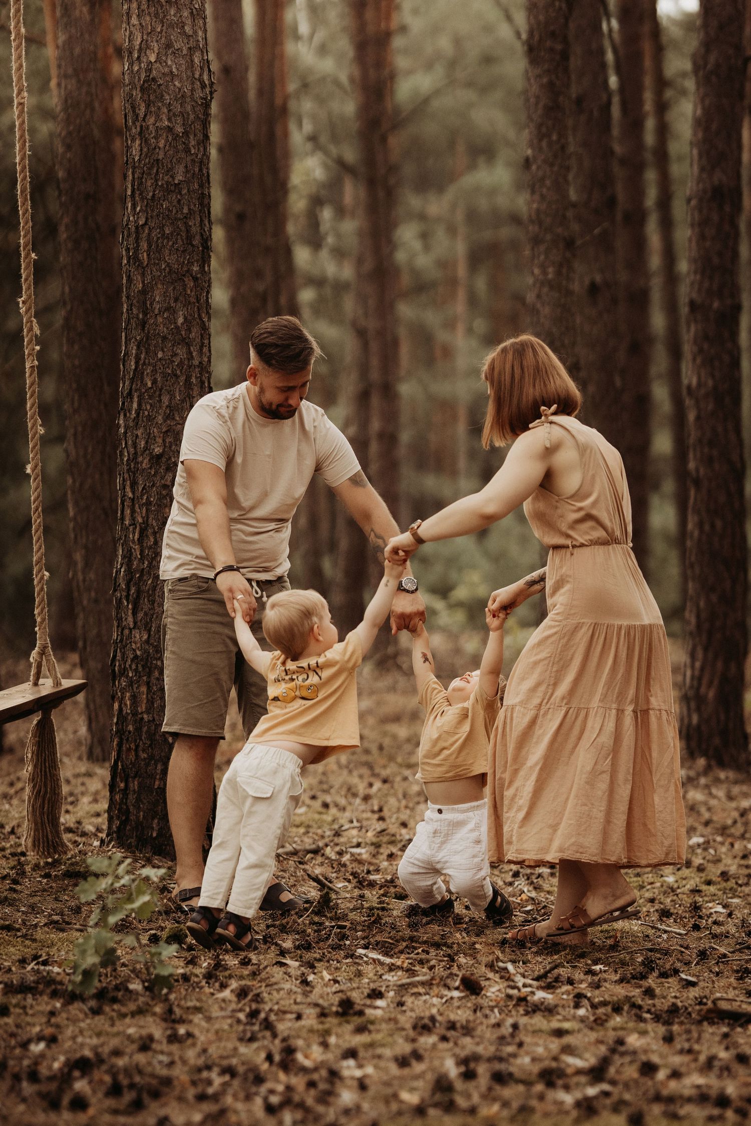 Family holds hands and spins together in the woods during a playful outdoor photoshoot in Swadlincote.