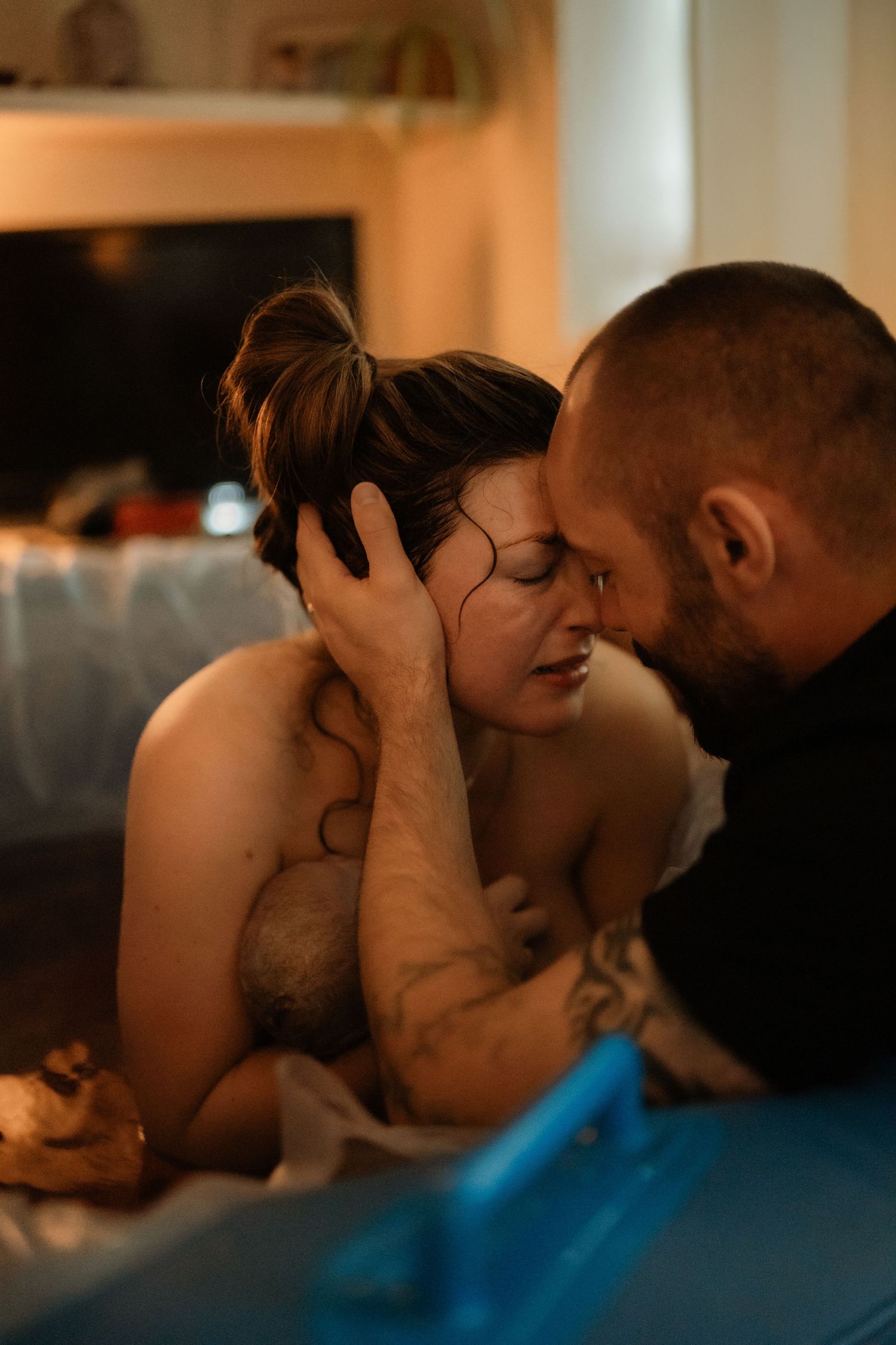 Partner comforting a birthing parent after delivery during an intimate documentary home birth session.