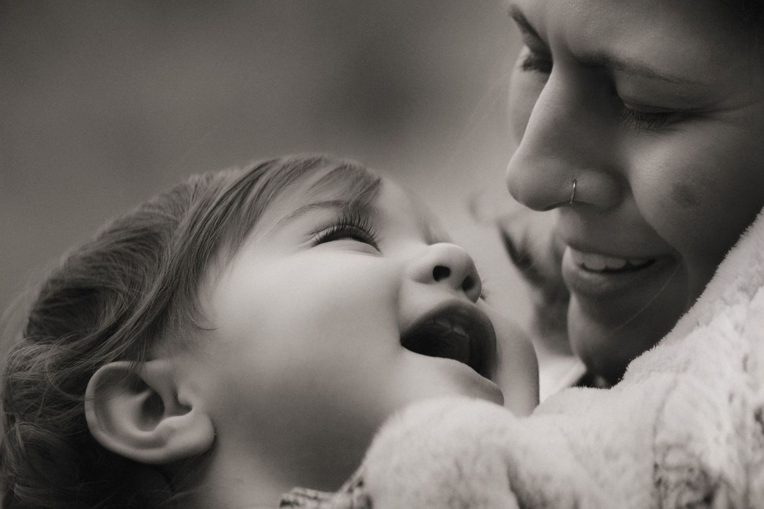 Mother and daughter share a joyful moment, smiling closely during a heartfelt motherhood photoshoot in the Midlands.