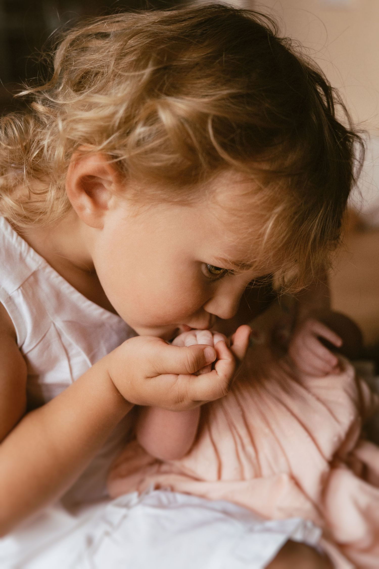 Older sibling gently touching a newborn’s hand during an in-home lifestyle newborn and family photography session.Detail shoot in Thurlaston
