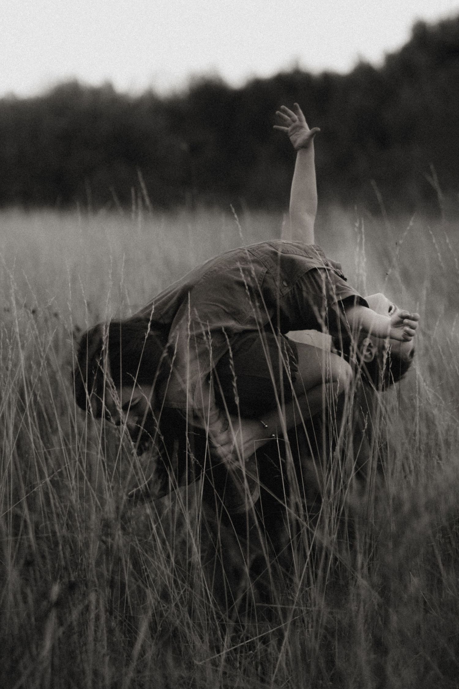 Black-and-white portrait of mother lifting her child in tall meadow grass – timeless family storytelling.