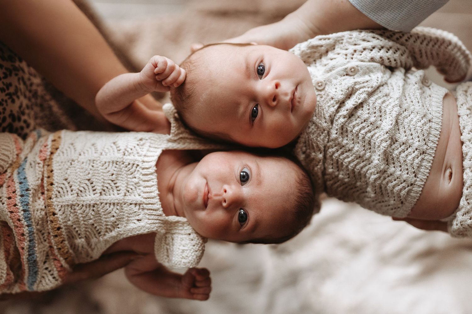 Twin newborns lying side by side, photographed naturally during an intimate storytelling photoshoot.