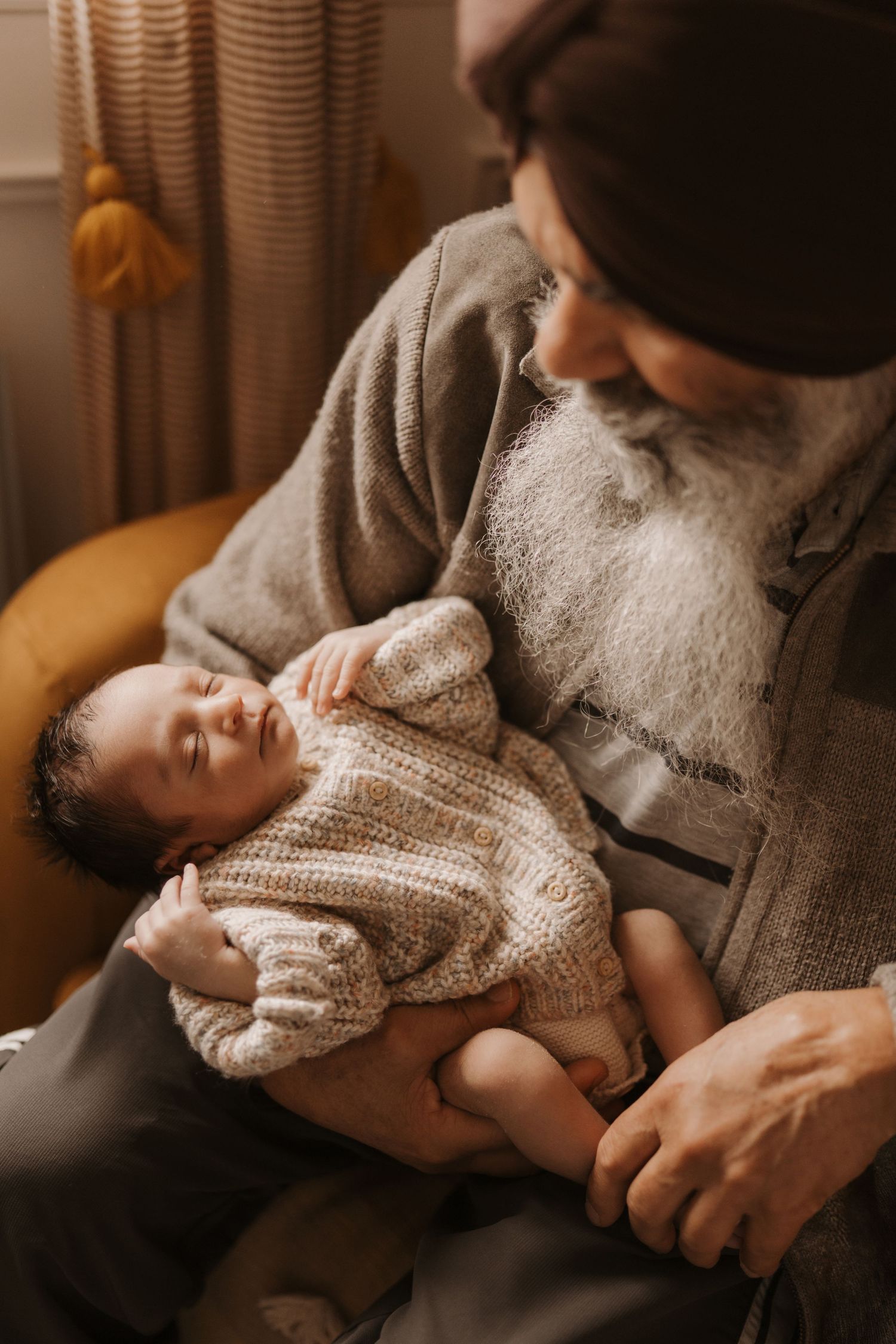 Grandparent holding a newborn during a calm lifestyle newborn photoshoot at home.