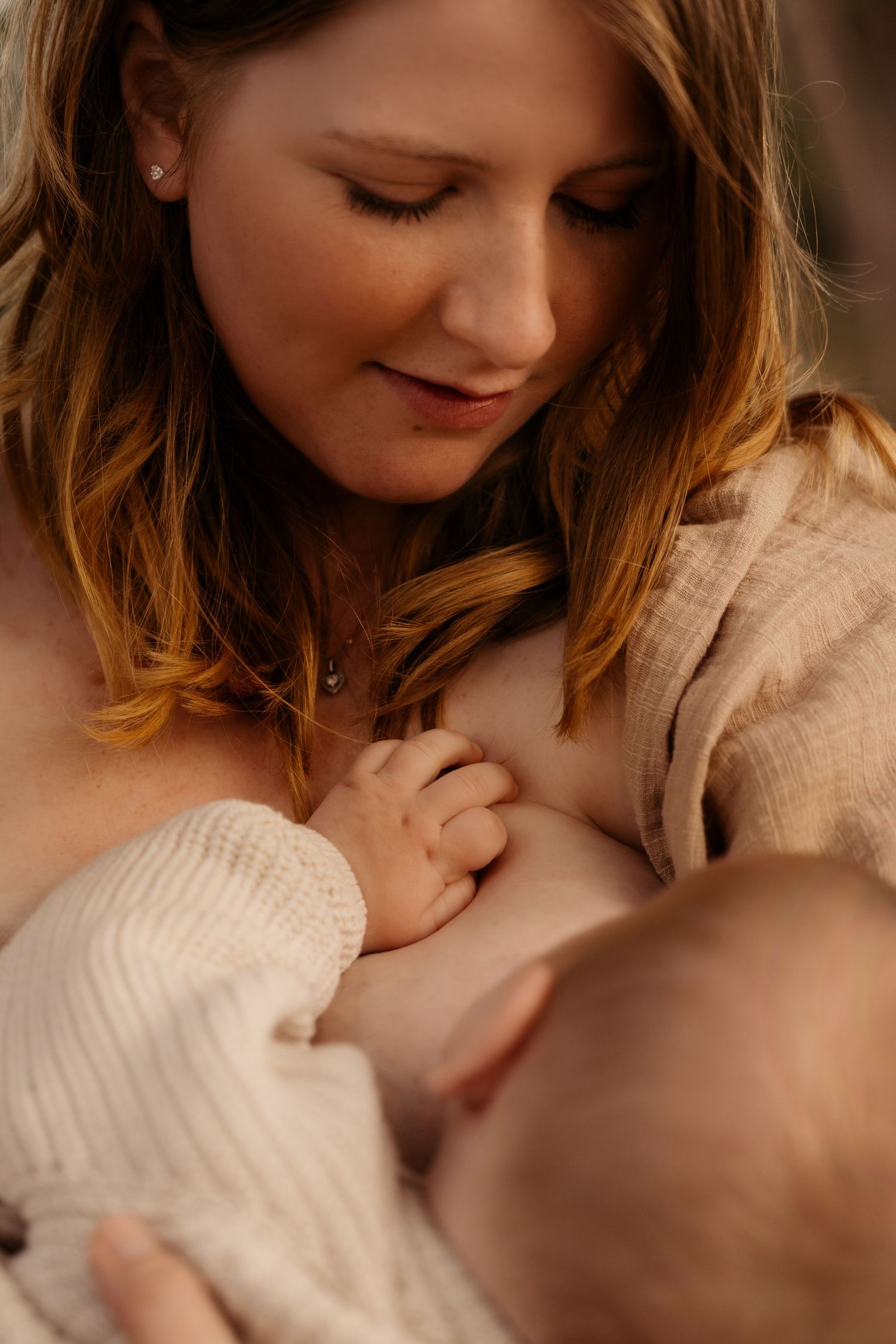 Tender breastfeeding moment bathed in golden light – captured by Swadlincote family photographer.