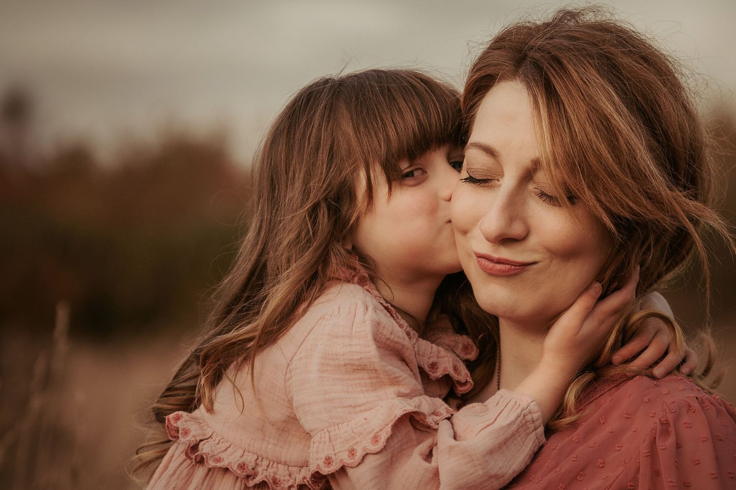Child kissing their mother’s cheek during a warm documentary family photography session outdoors.