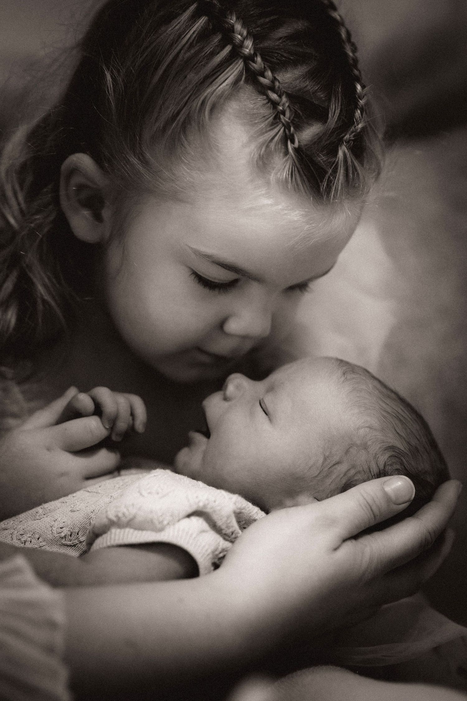 Older sibling gently cradling a newborn’s face, a quiet bond captured during a storytelling family photoshoot with Soft Stories by Angela