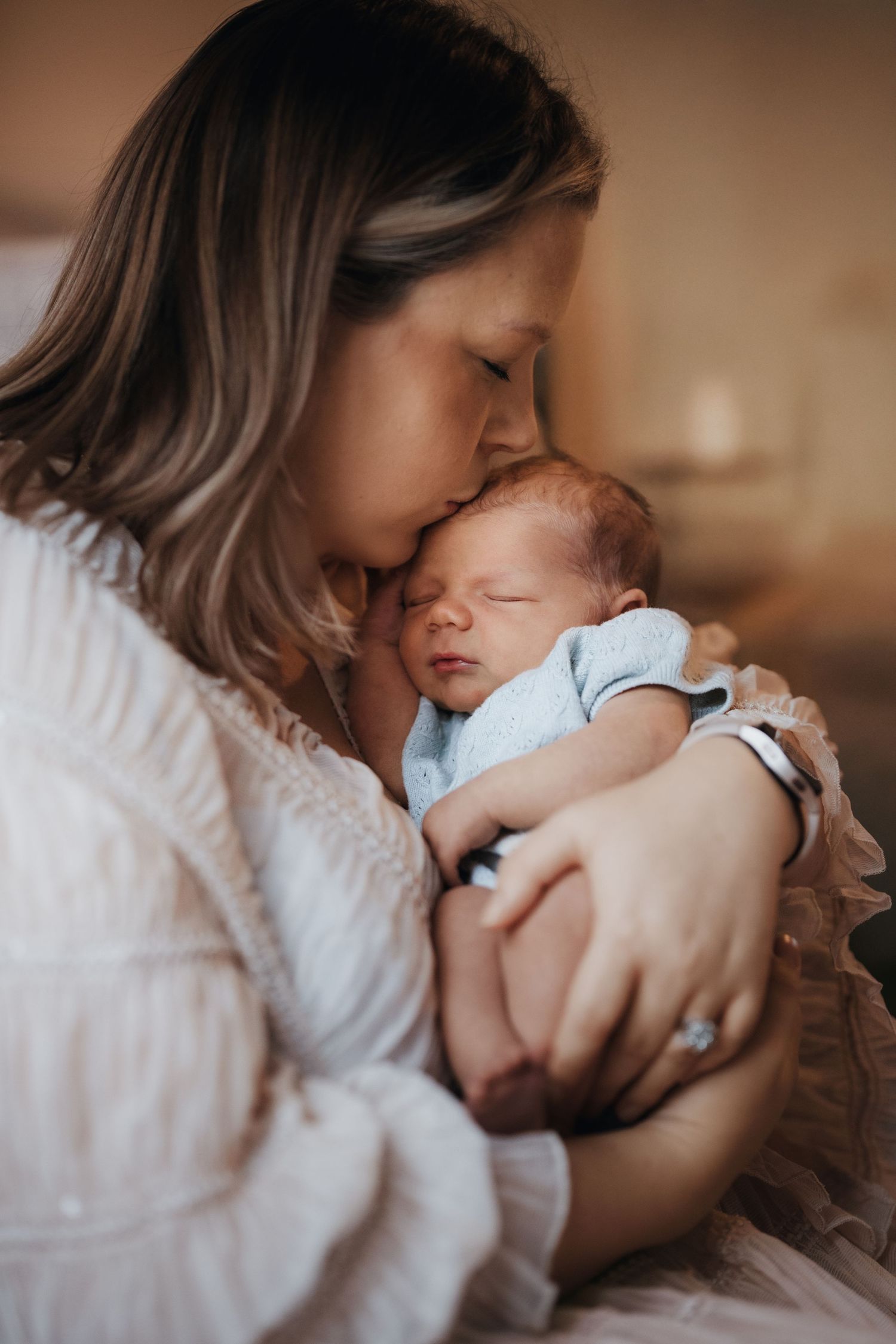 Mother holding her newborn close, sharing a quiet kiss during a calm lifestyle newborn photoshoot at home in Tamworth
