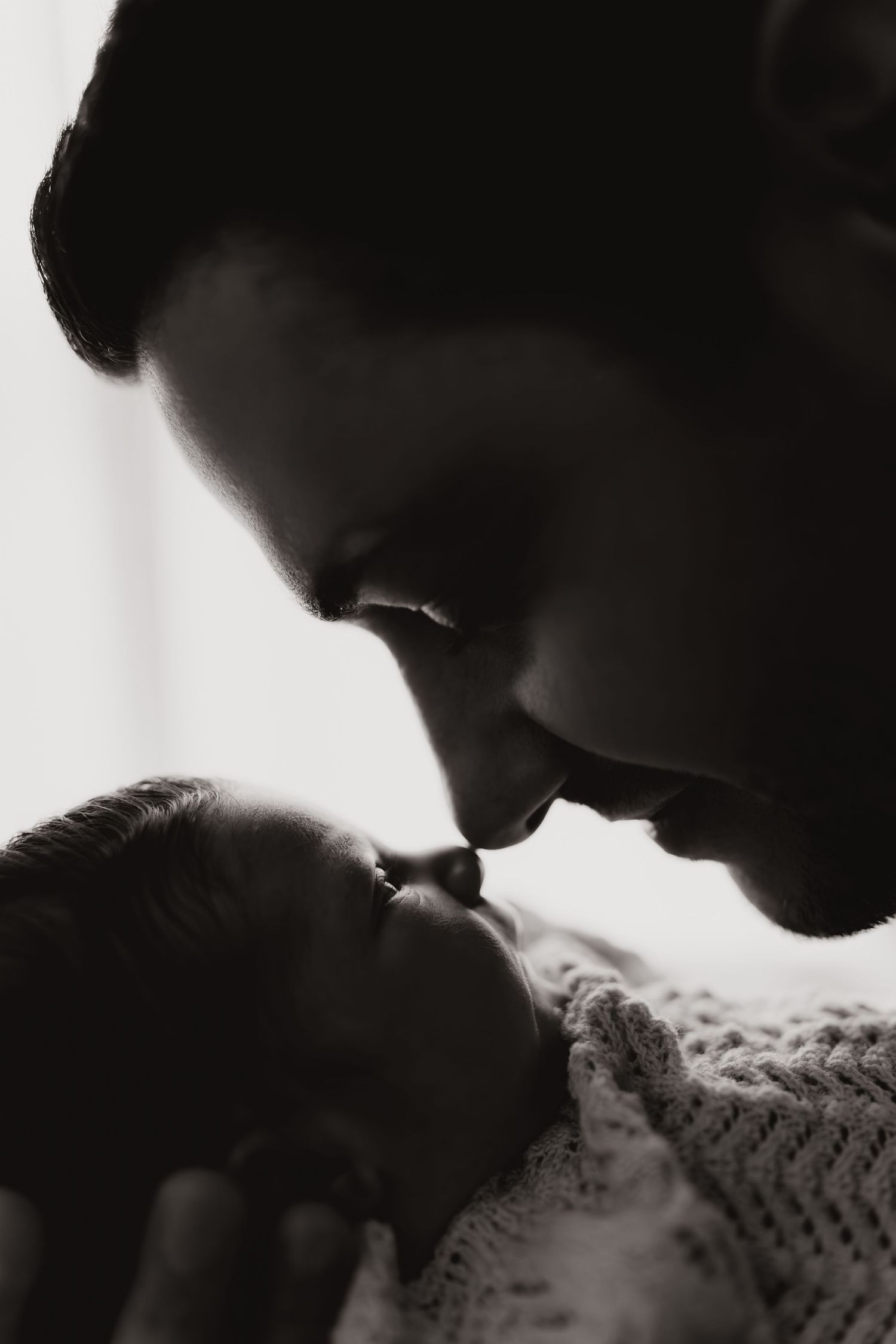 Parent touching noses with their newborn during an intimate storytelling newborn photoshoot in black and white.