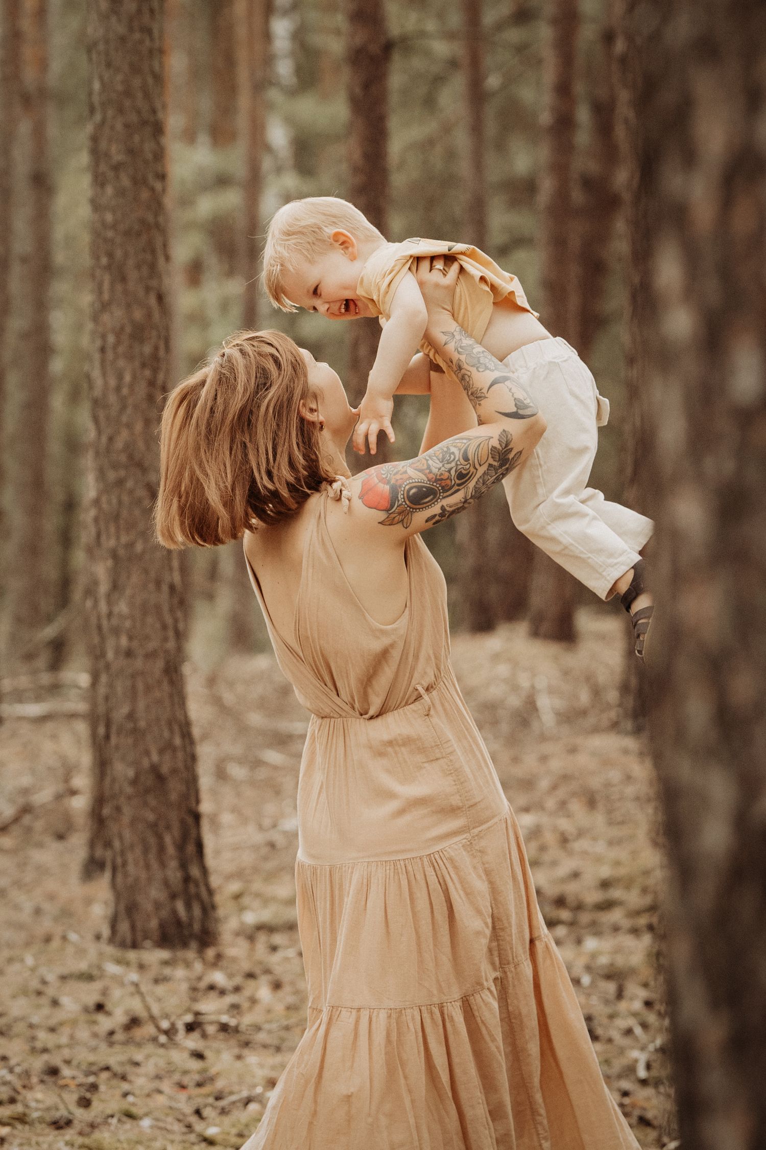 Mum lifts her baby high in a forest during a joyful motherhood and family photoshoot in Swadlincote.