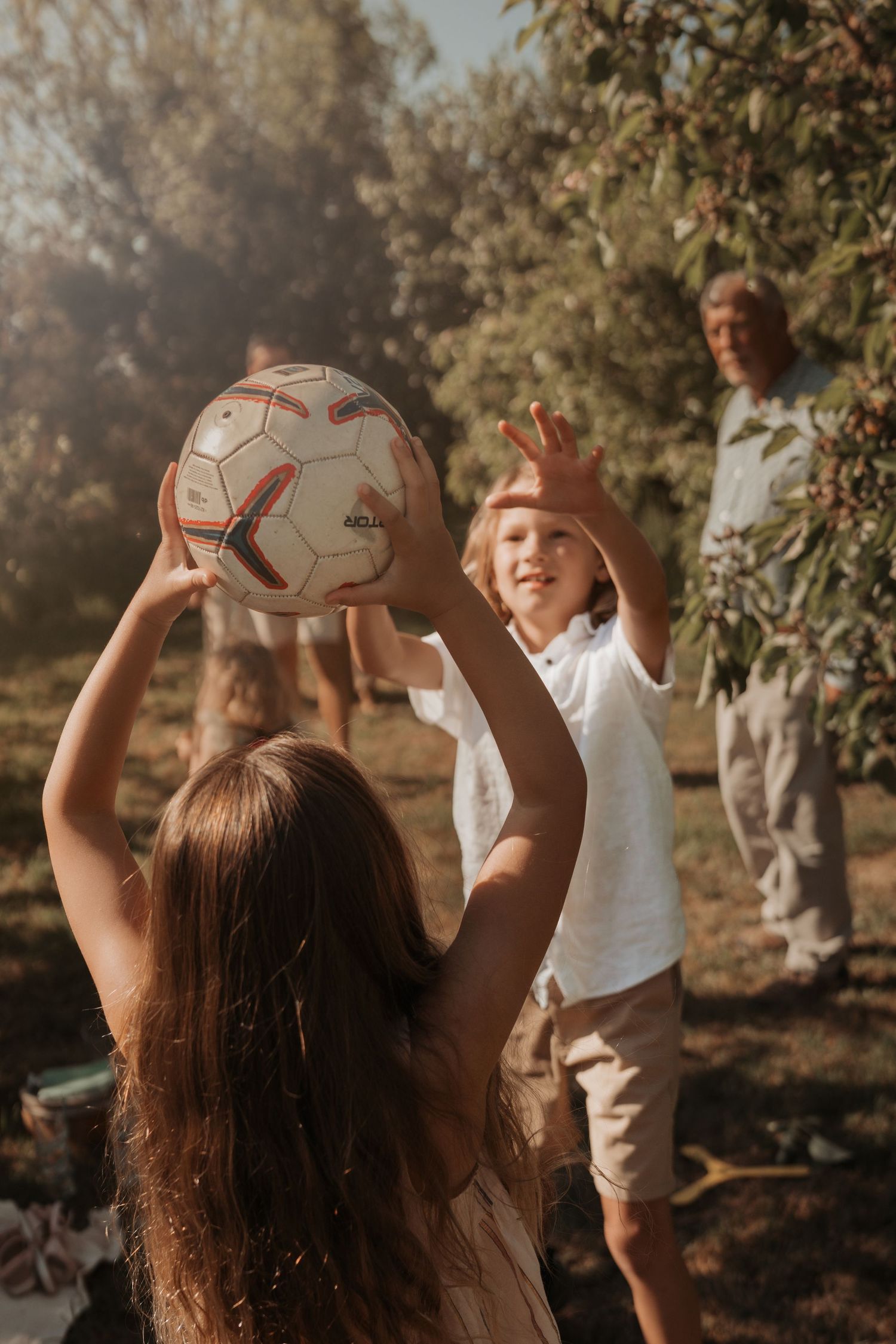 Family plays catch with a football in the garden during a joyful multigenerational photography session ihn Lichfield
