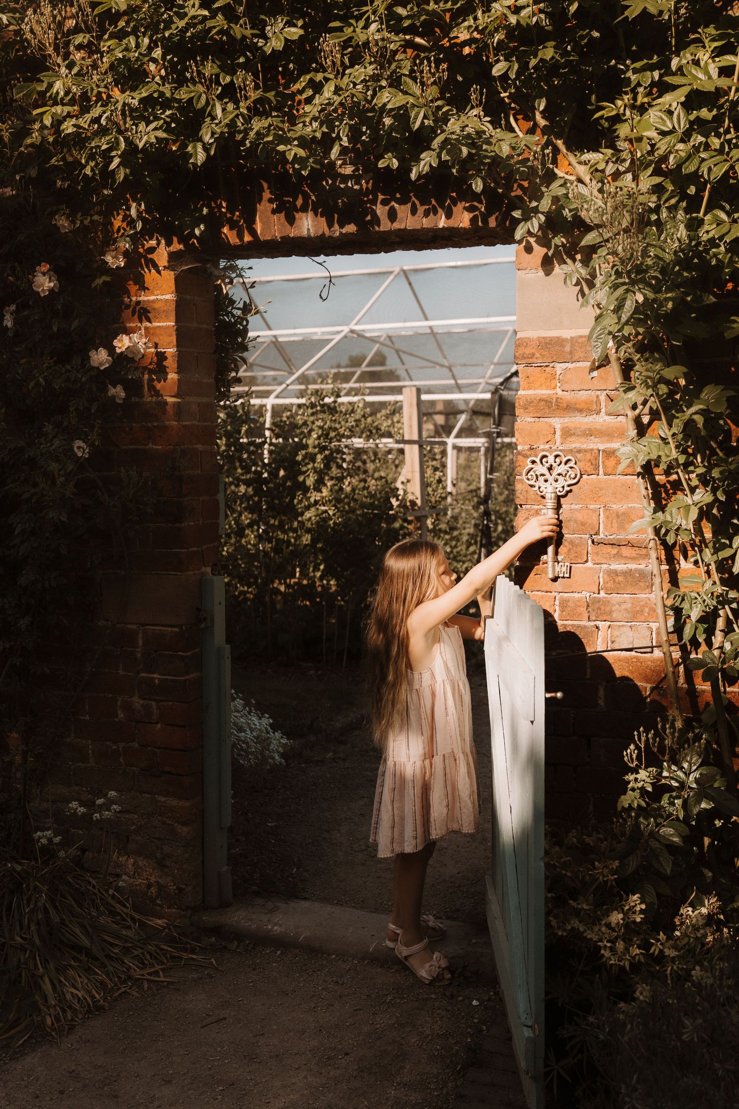 Girl in a tulle dress walks through a brick garden archway during a dreamy storytelling photoshoot in Tamworth.