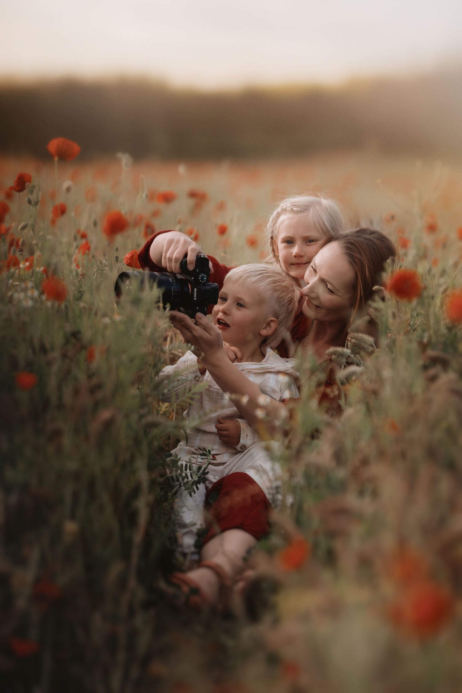 Family sitting in a wildflower field with young children exploring and playing, photographed in natural light during an outdoor family sessi