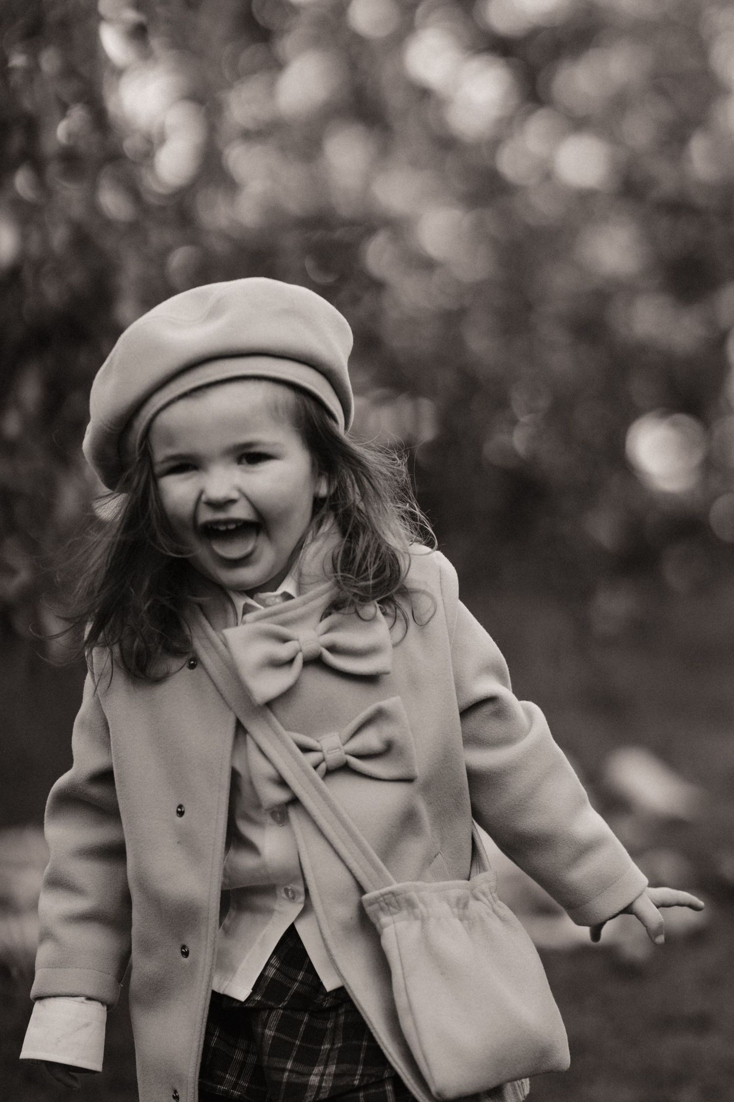 Black and white portrait of a young child wearing a coat and beret, looking toward the camera with a gentle expression