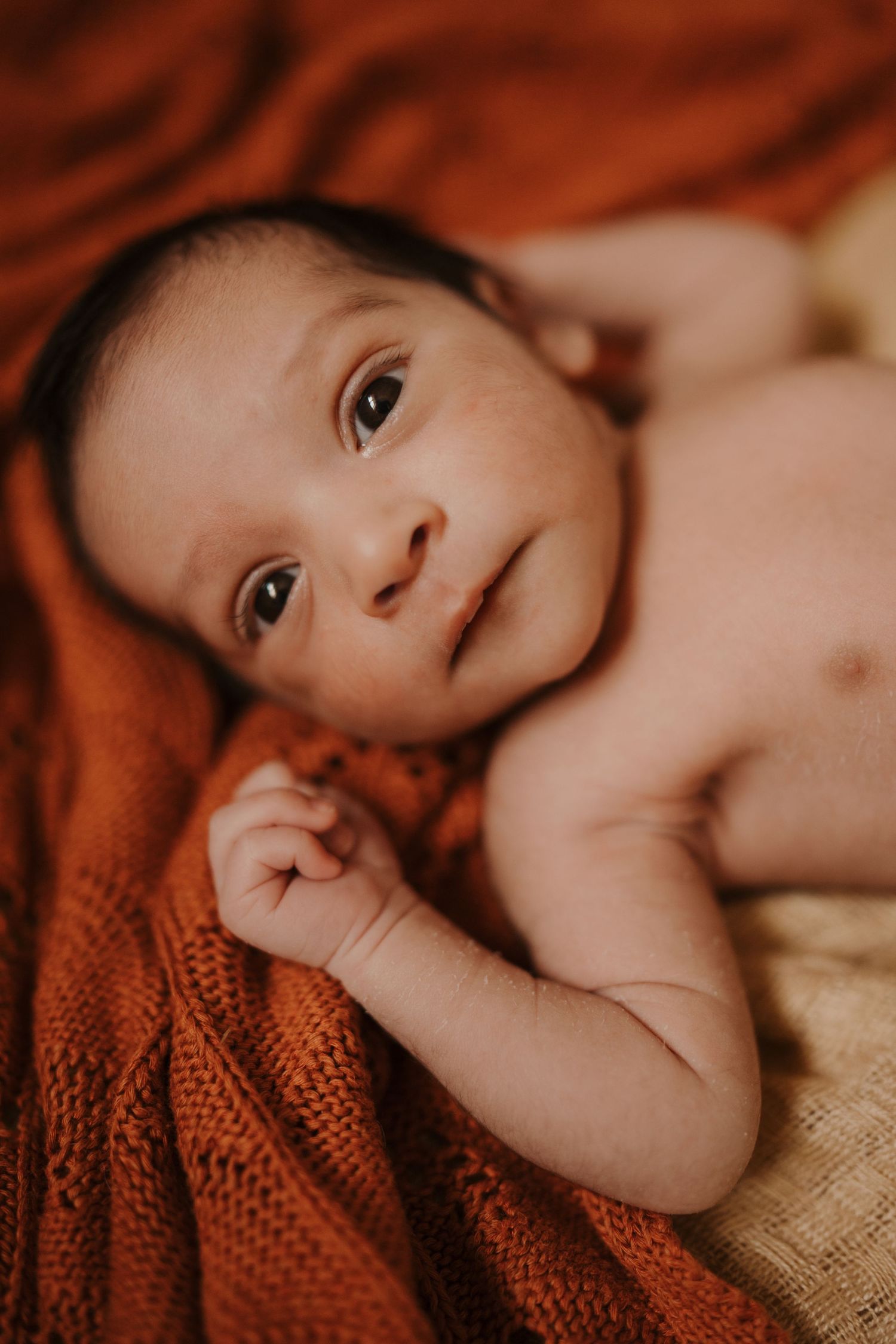 Newborn lying on textured blankets during a calm lifestyle newborn photoshoot at home in Stoke