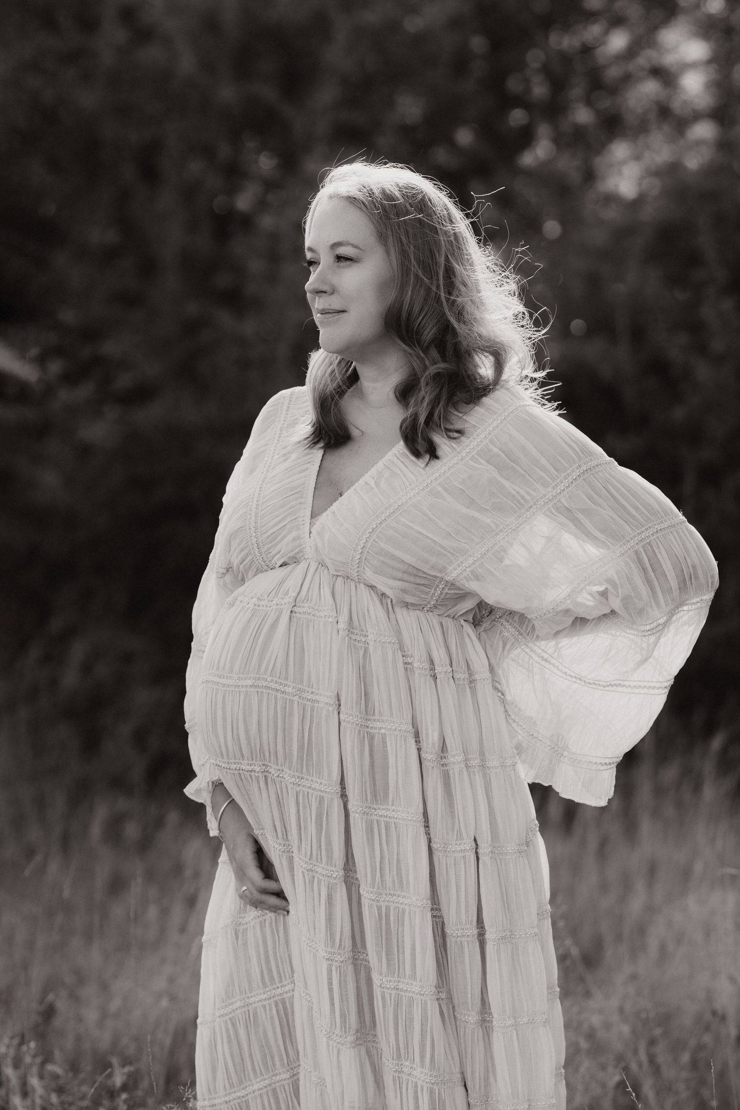 Pregnant parent standing in a field during a calm outdoor documentary maternity photography session with Angela Palka