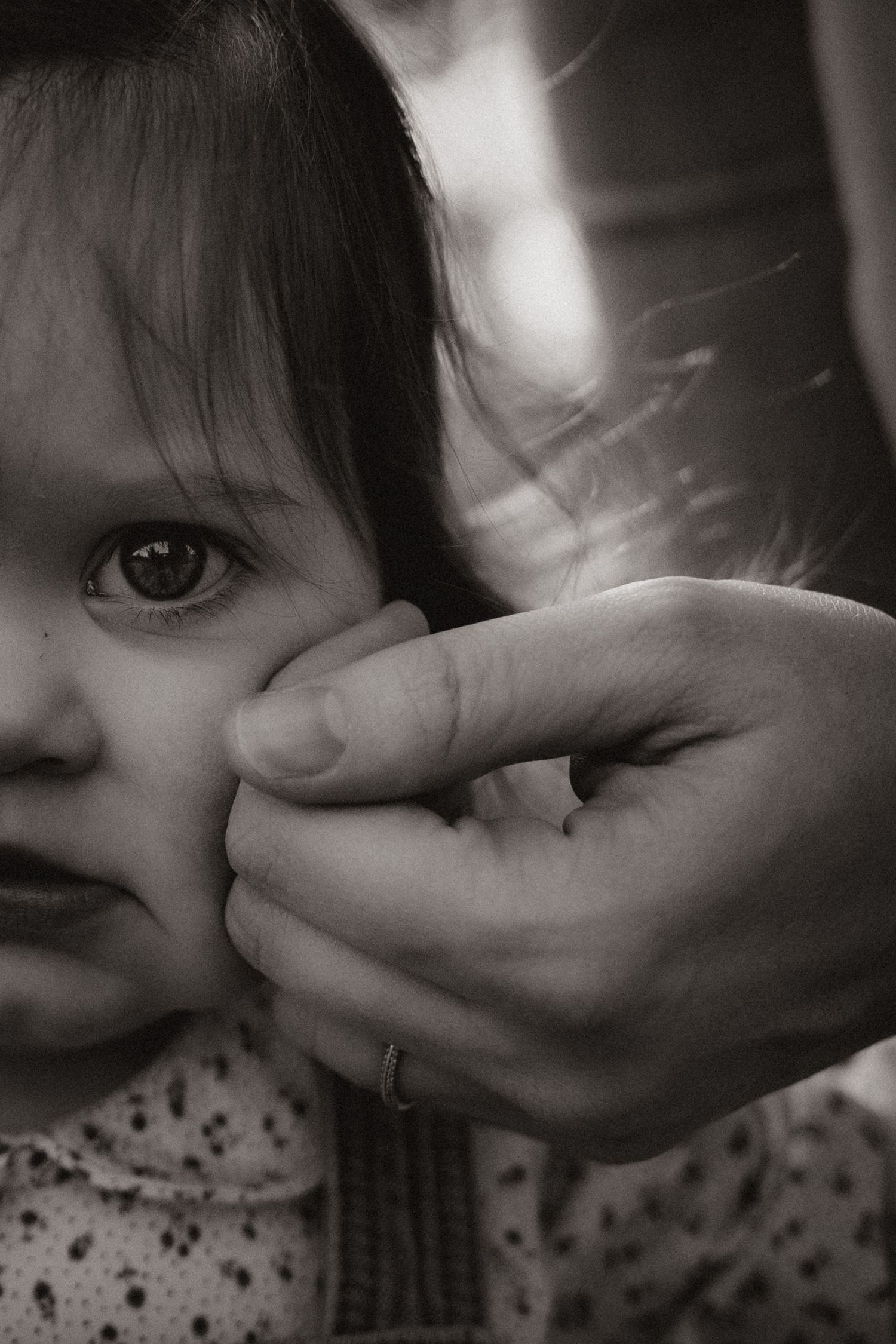 Toddler looks into the camera while holding mum's hand during a gentle mother's day photography session in Tamworth
