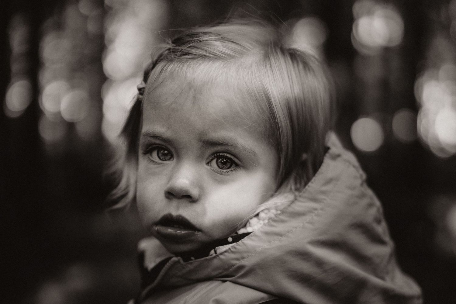 Close-up portrait of a young child in soft light during a black and white documentary childhood photoshoot at Little Wildlings Natureplay