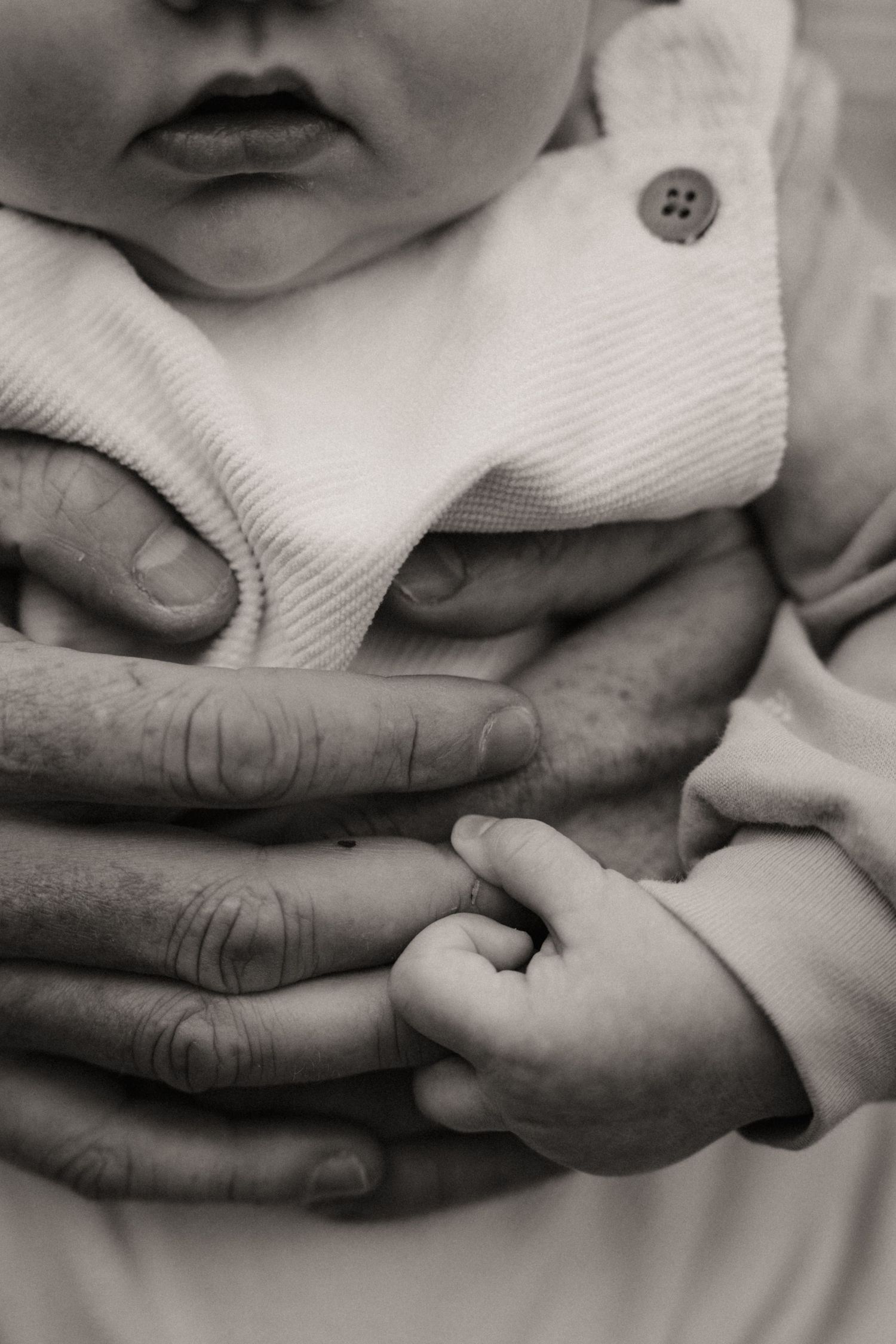 Close-up of baby’s tiny hands resting in a parent’s palms during a heartfelt newborn storytelling shoot.