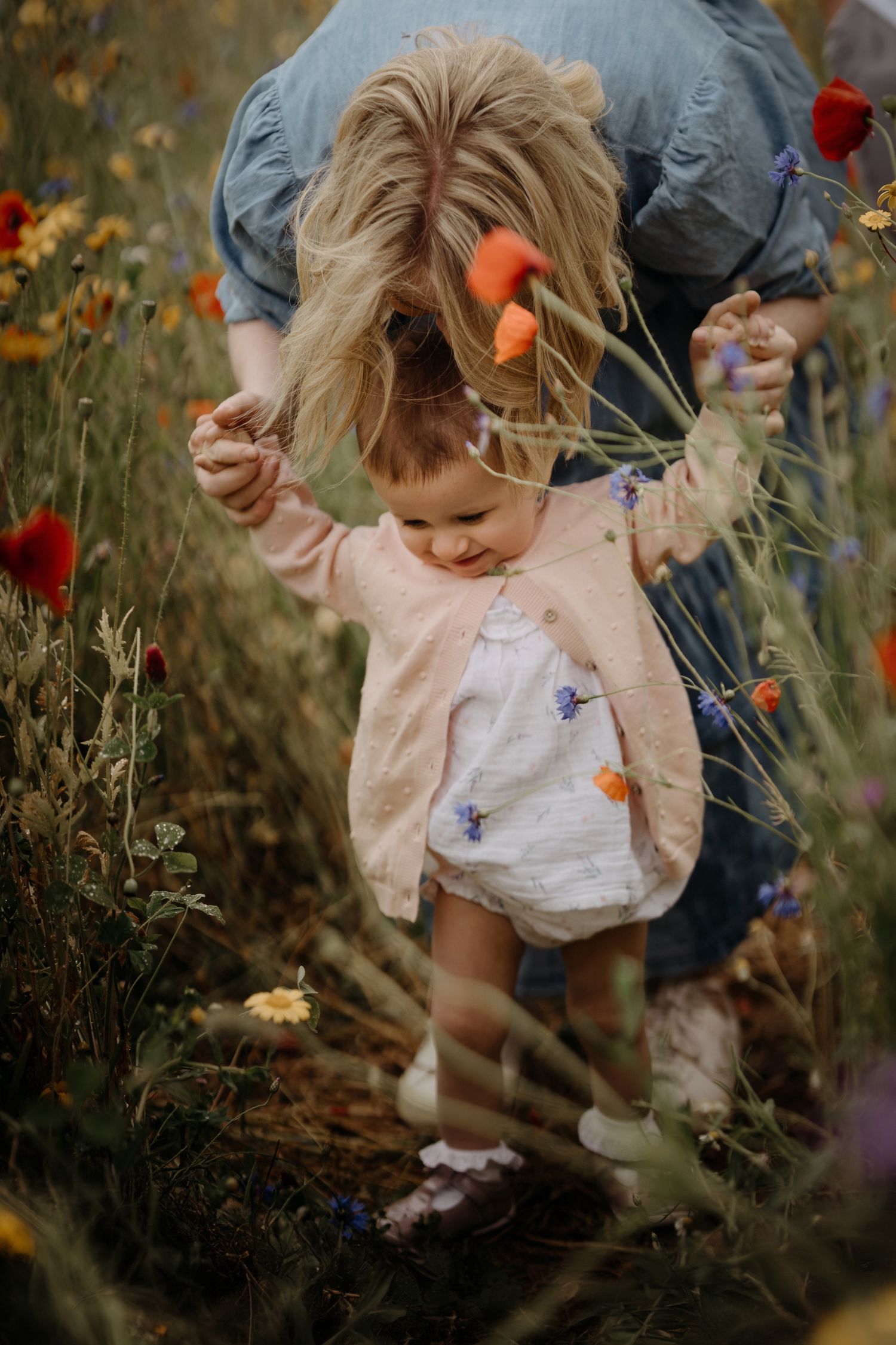 mum holding baby's hands during confetti field photoshoot with soft stories by angela