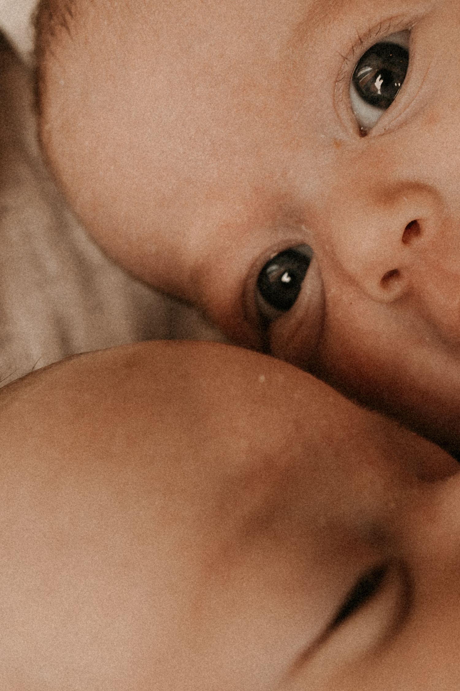 Intimate close-up of twins resting together, photographed softly during a natural newborn photoshoot.
