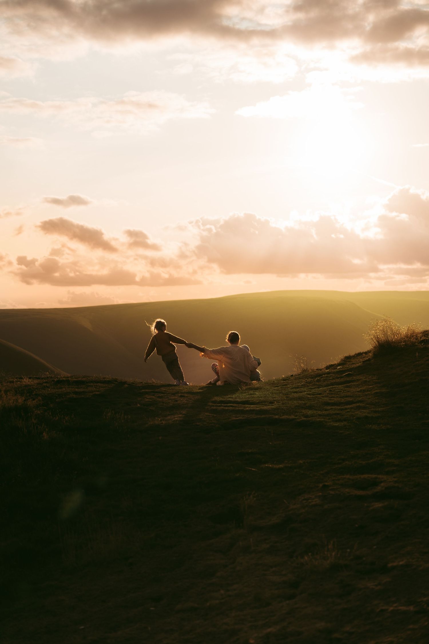 Family walks hand in hand over the hills at sunset during a dreamy family session on Mam Tor