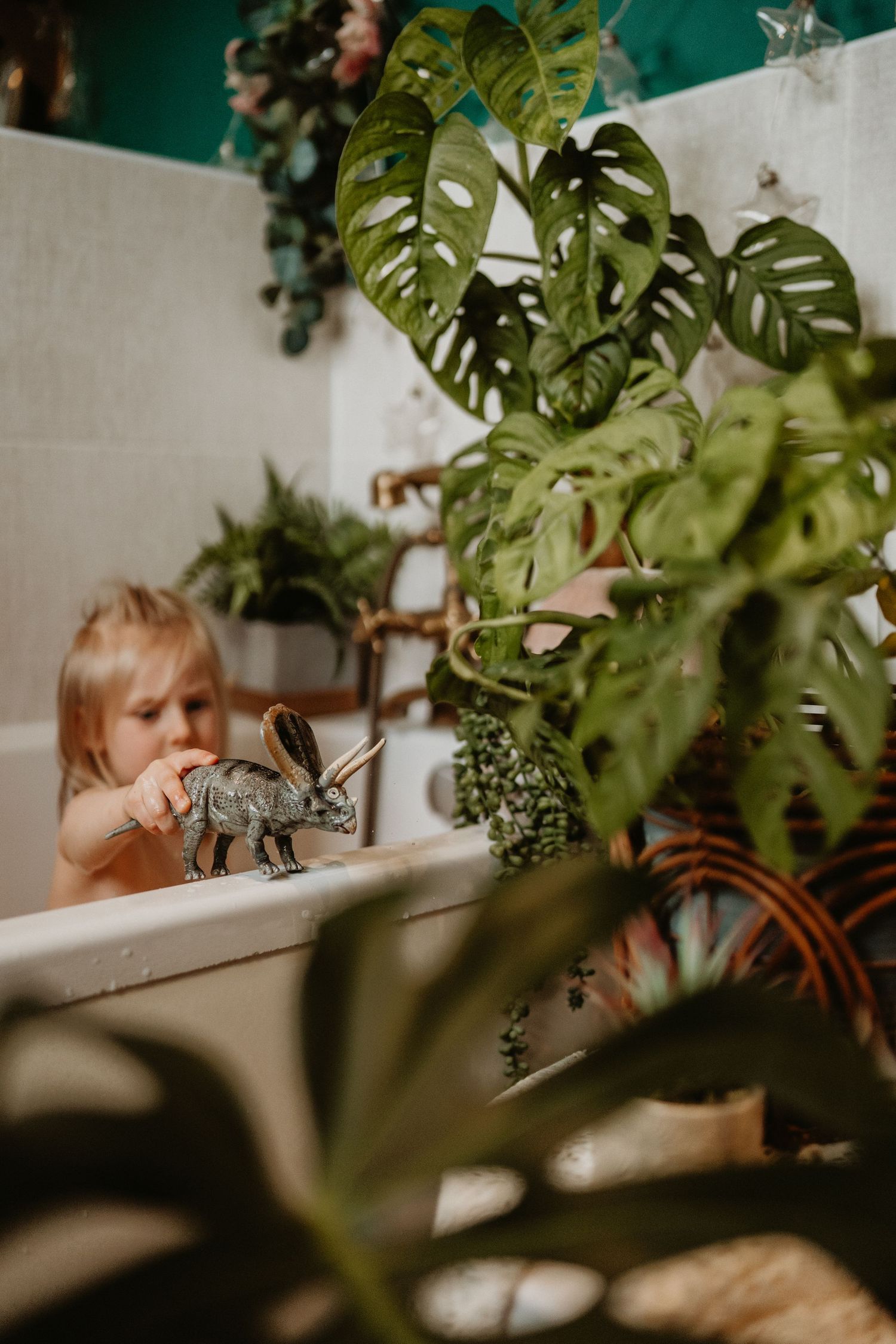 Child sitting among houseplants during a candid in-home documentary storytelling family photography moment in Swadlincote