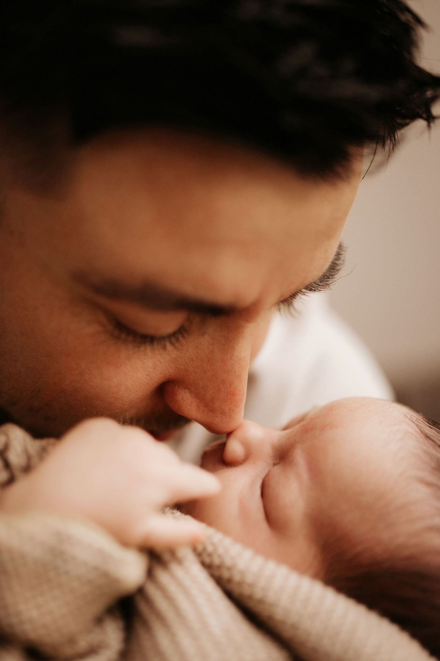 Parent kissing their newborn’s face during an intimate in-home lifestyle newborn photography moment.