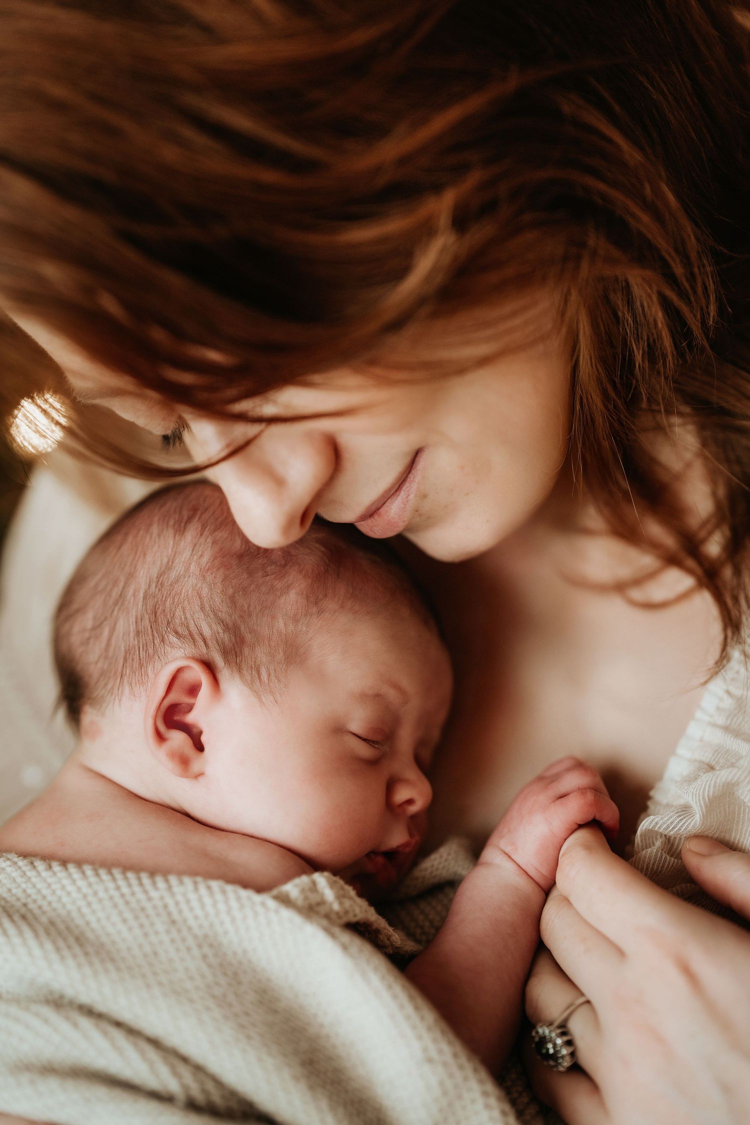 Mother holding her sleeping newborn close during a quiet lifestyle newborn photoshoot at home in Ashby de la Zouch with Soft Stories