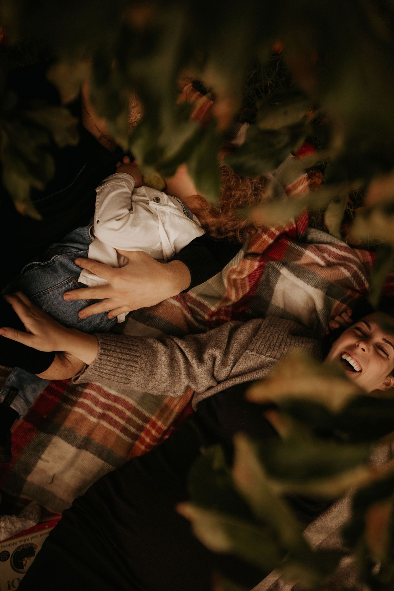 Expecting mother lies down among apple trees, gently holding her bump in warm autumn tones.