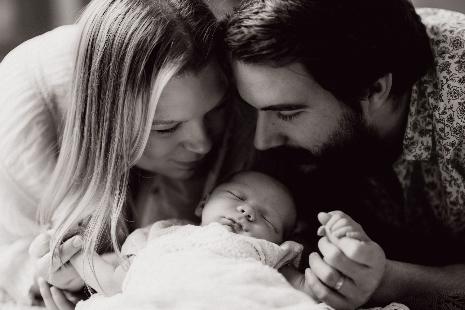 Parents cuddling their newborn during an intimate in-home lifestyle newborn and family photography session in Tamworth