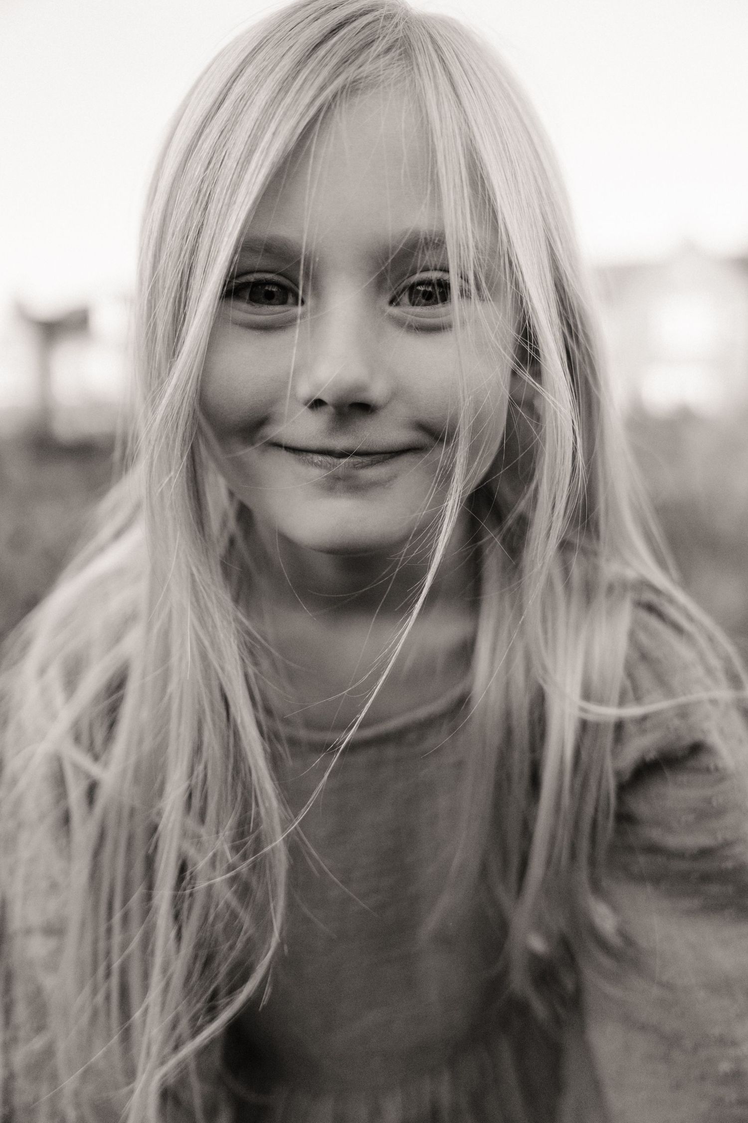 Black and white portrait of a child with long hair and a soft smile in the Midlands