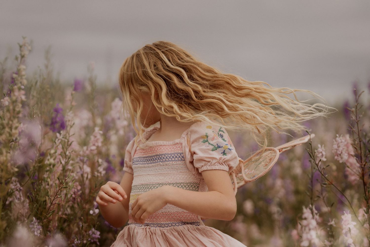 girl dancing in delphinium field at confetti flower petal field