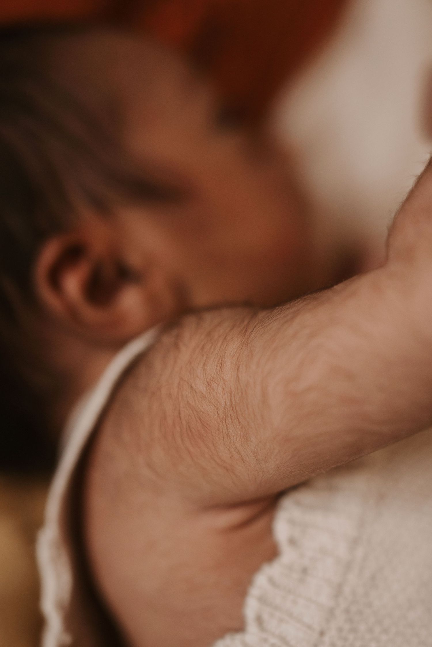 Newborn resting against a parent’s shoulder during a quiet storytelling newborn photoshoot. detail macro shoot by Soft Stories by Angela
