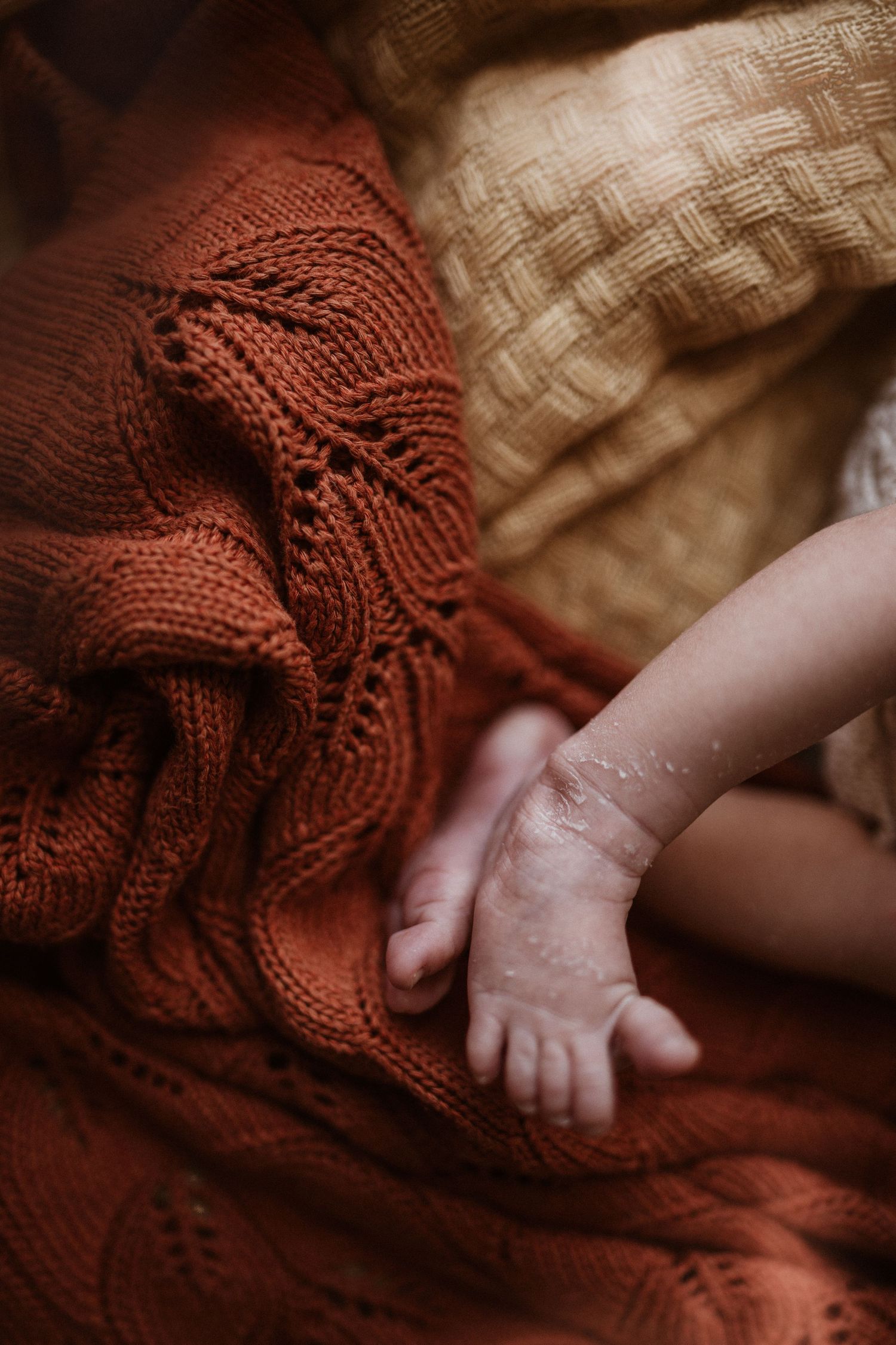 Newborn hand resting on textured blankets during a soft storytelling newborn photoshoot at home in Stoke on Trent