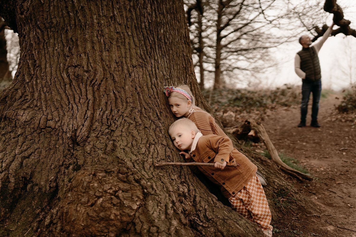 Two siblings Two siblings lean against a tree trunk during alean against a tree trunk during a woodland storytelling session in Swadlincote.