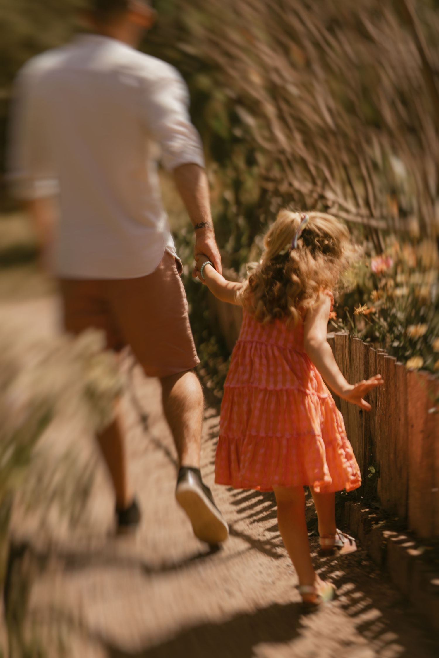 A daughter happily dancing in the flower field, holding hands with her dad