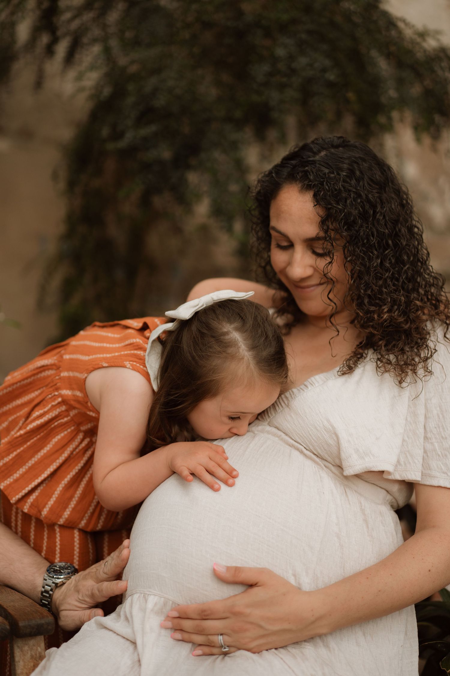 Expecting mother and daughter share a soft moment, hands over bump, surrounded by calm light in Melbourne