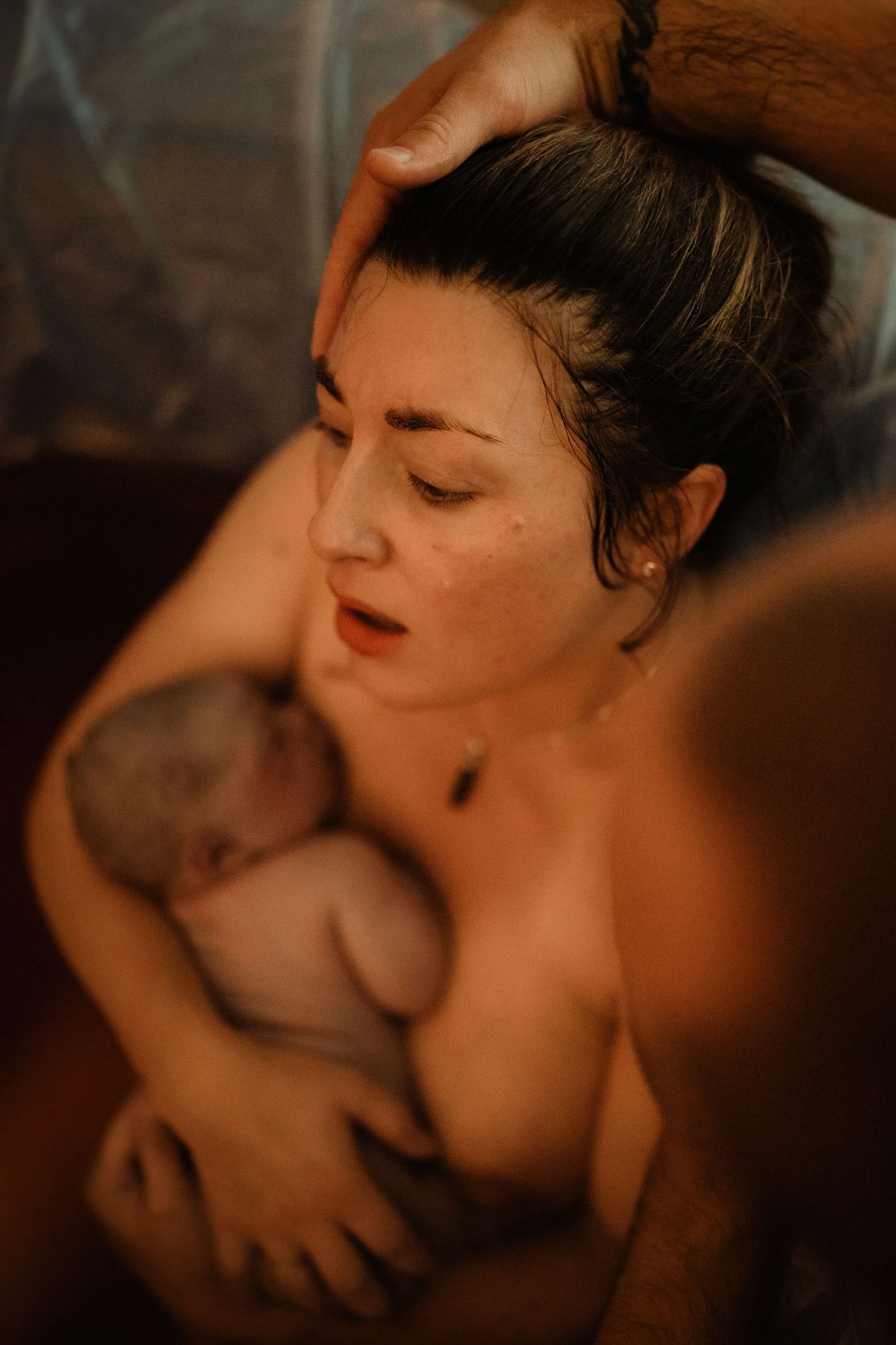 Partner comforting a birthing parent after delivery during an intimate documentary home birth photoshoot