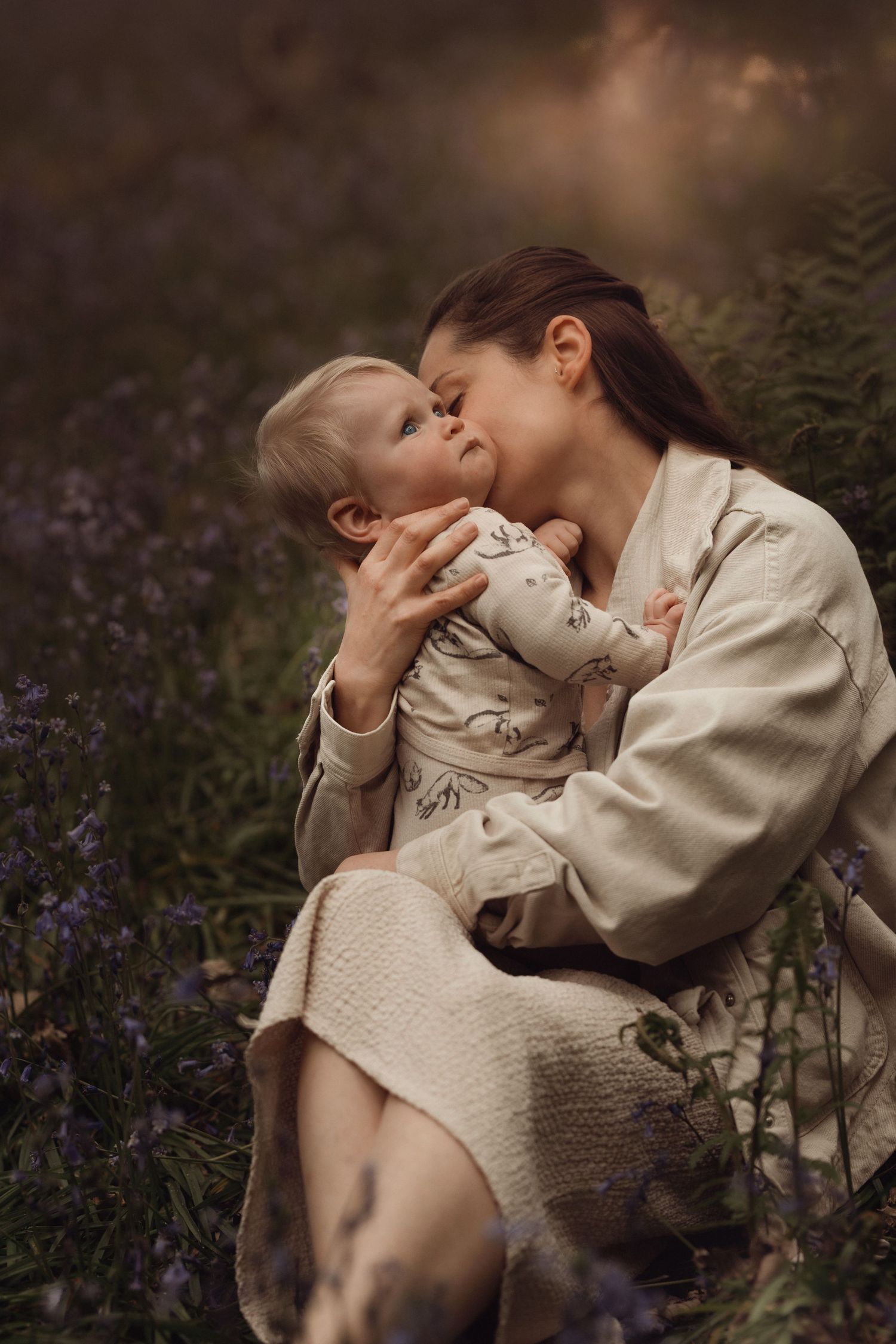 Mother kissing her baby in a field of bluebells, a quiet and intimate moment captured in natural light by Soft Stories by Angela