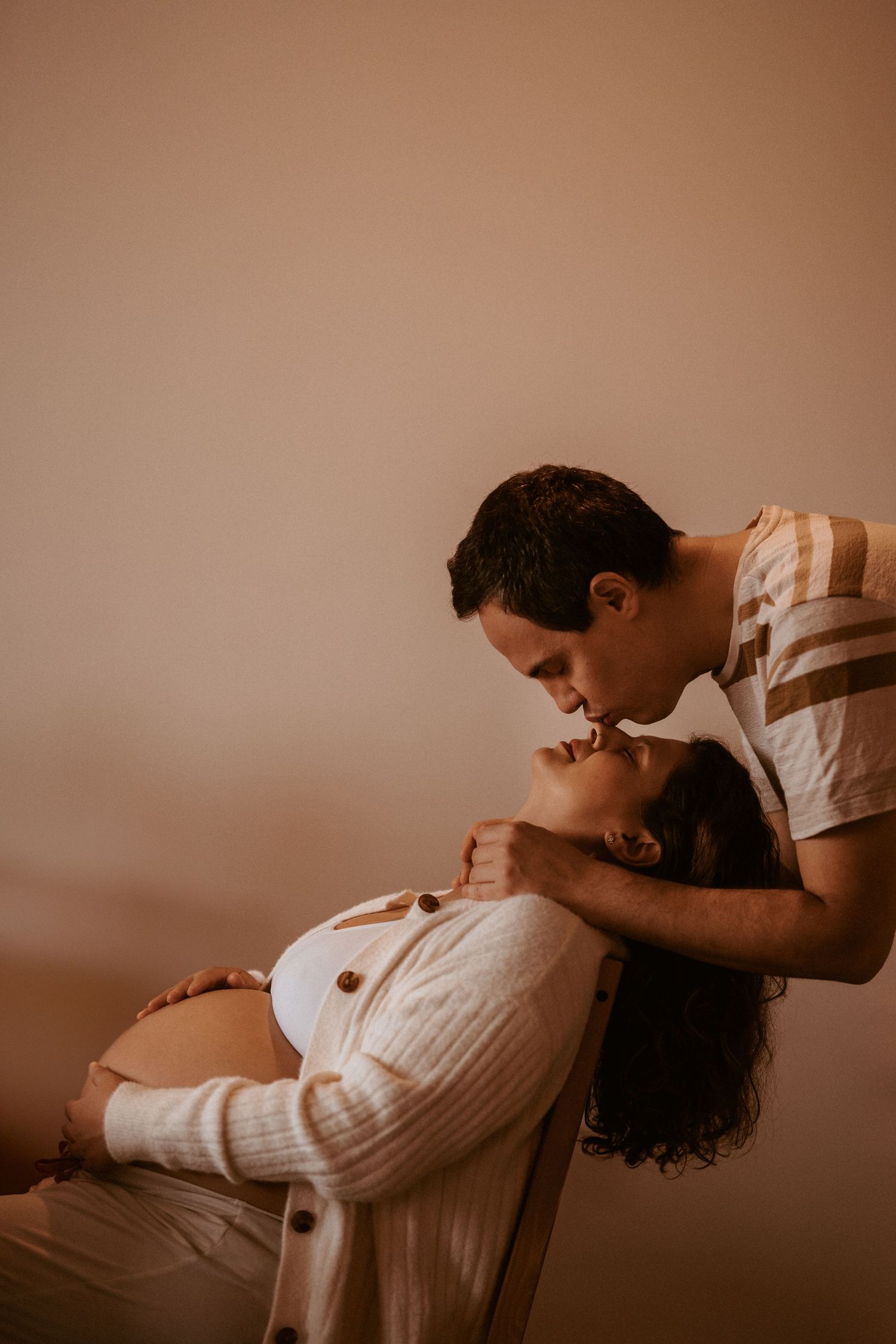 Couple cuddling together in soft natural light during a relaxed in-home maternity and family photography session in Stoke on Trent