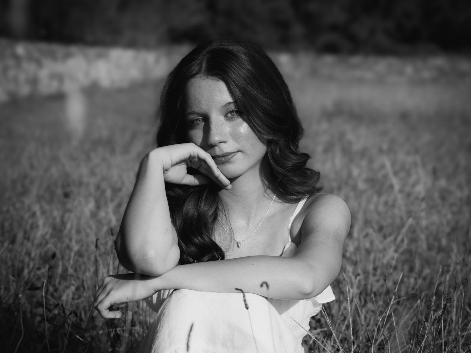Black and white portrait of a high school senior posing in a field of tall grass.